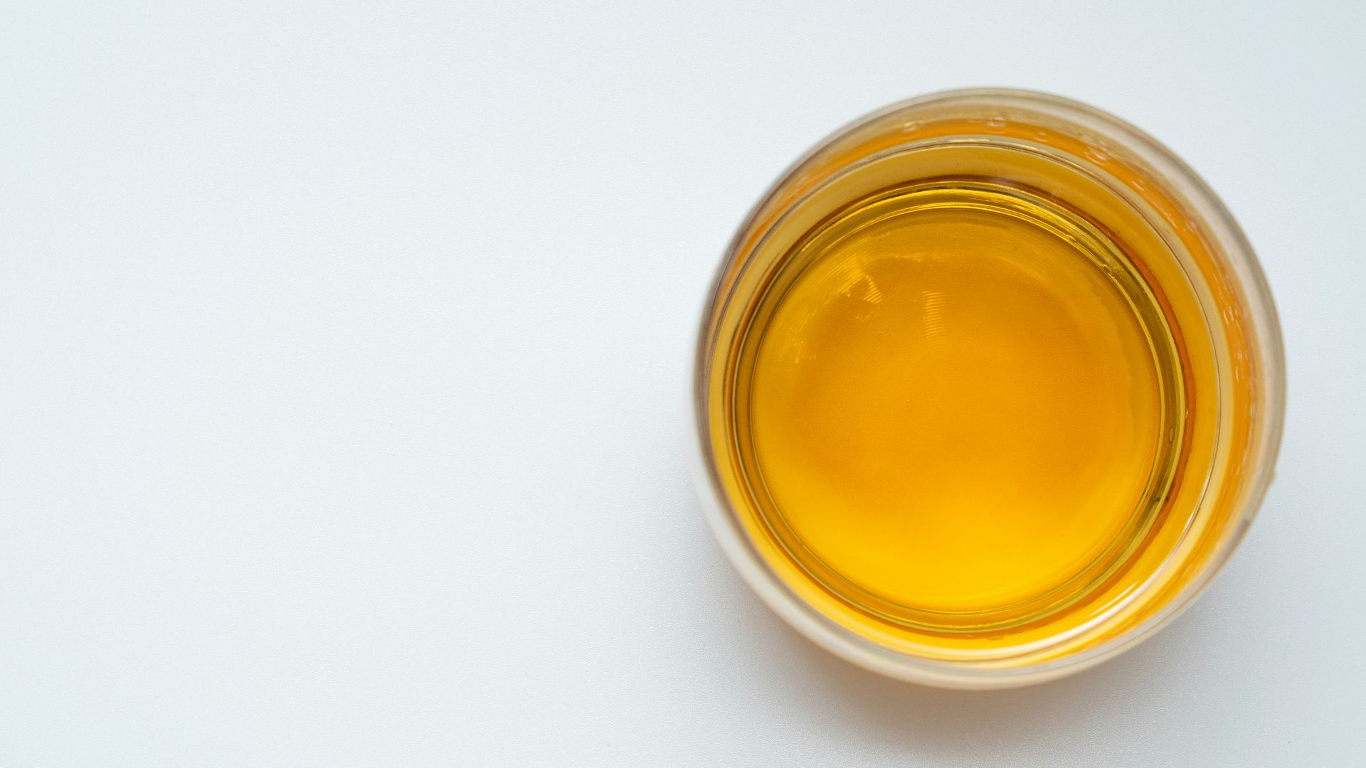 a glass filled with yellow liquid on top of a white table