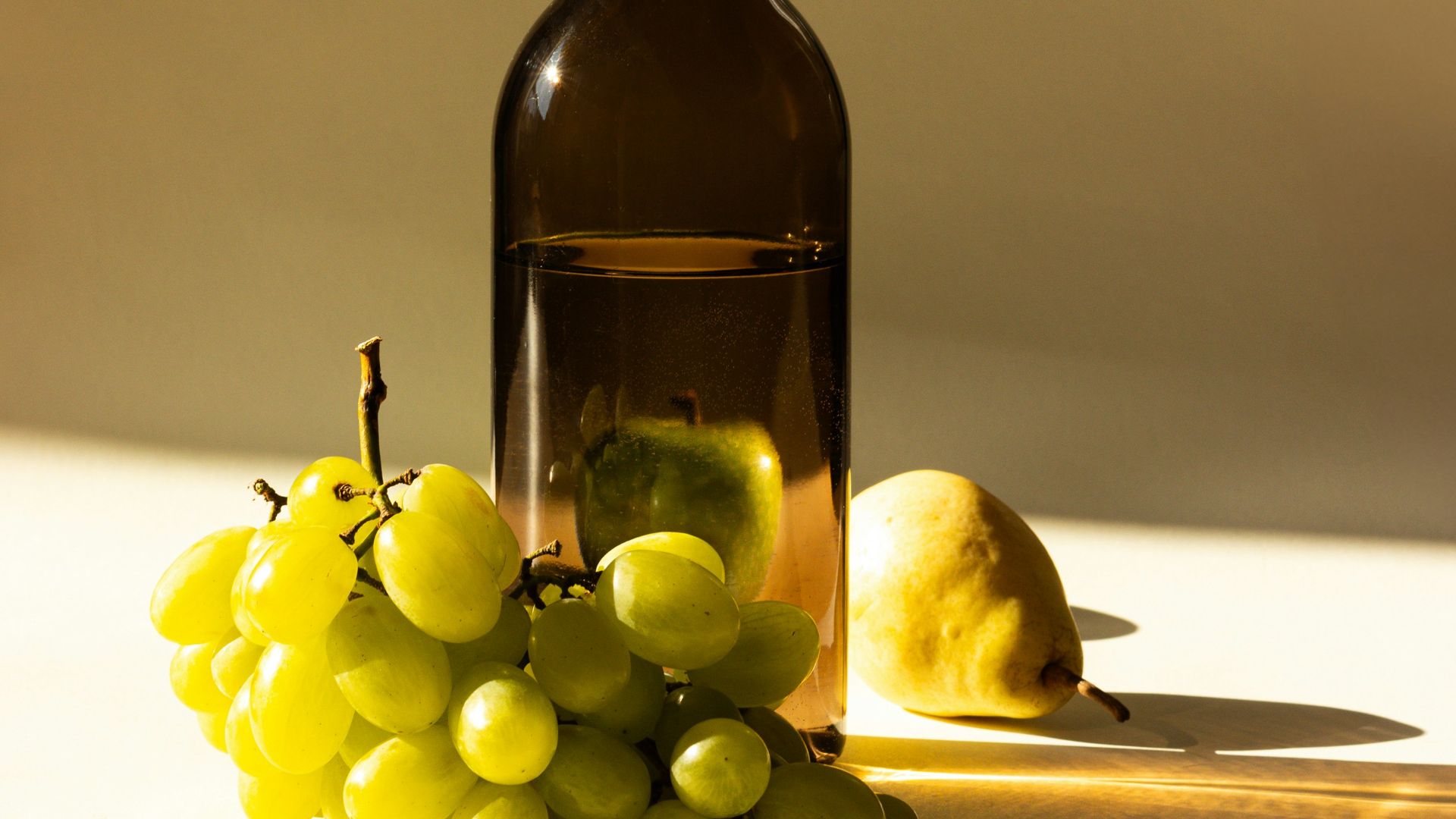 a bottle of wine next to a bunch of grapes