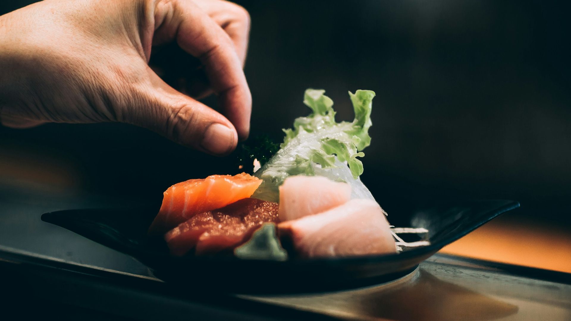 left hand picking vegetable on plate
