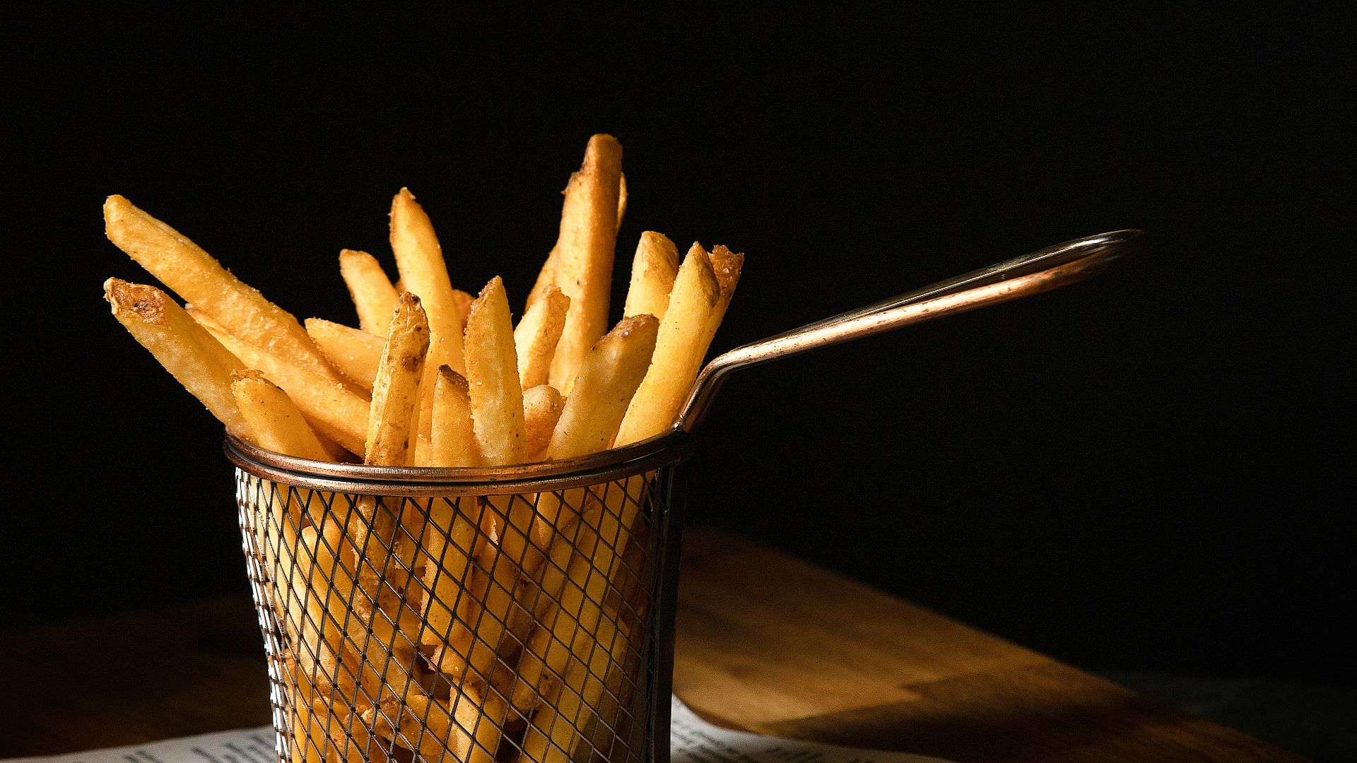 a basket of french fries sitting on top of a wooden table