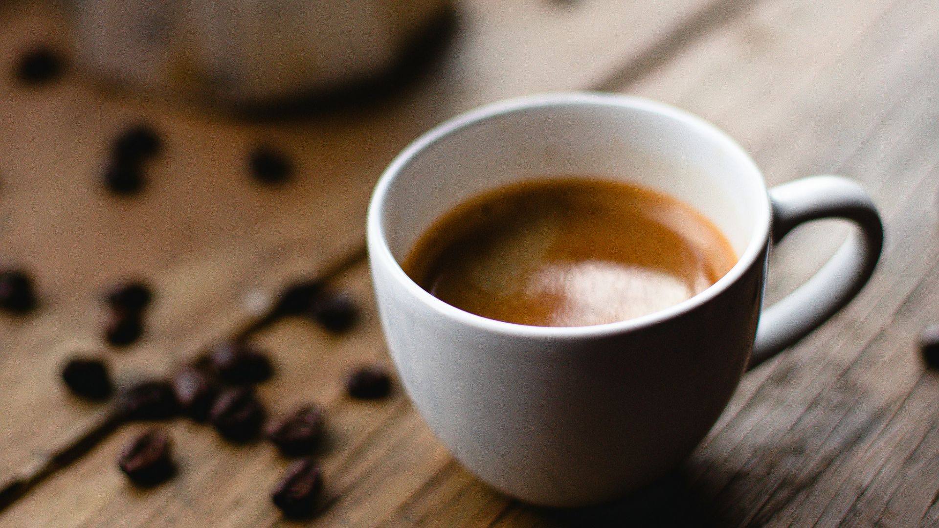 white ceramic mug with coffee on brown wooden table