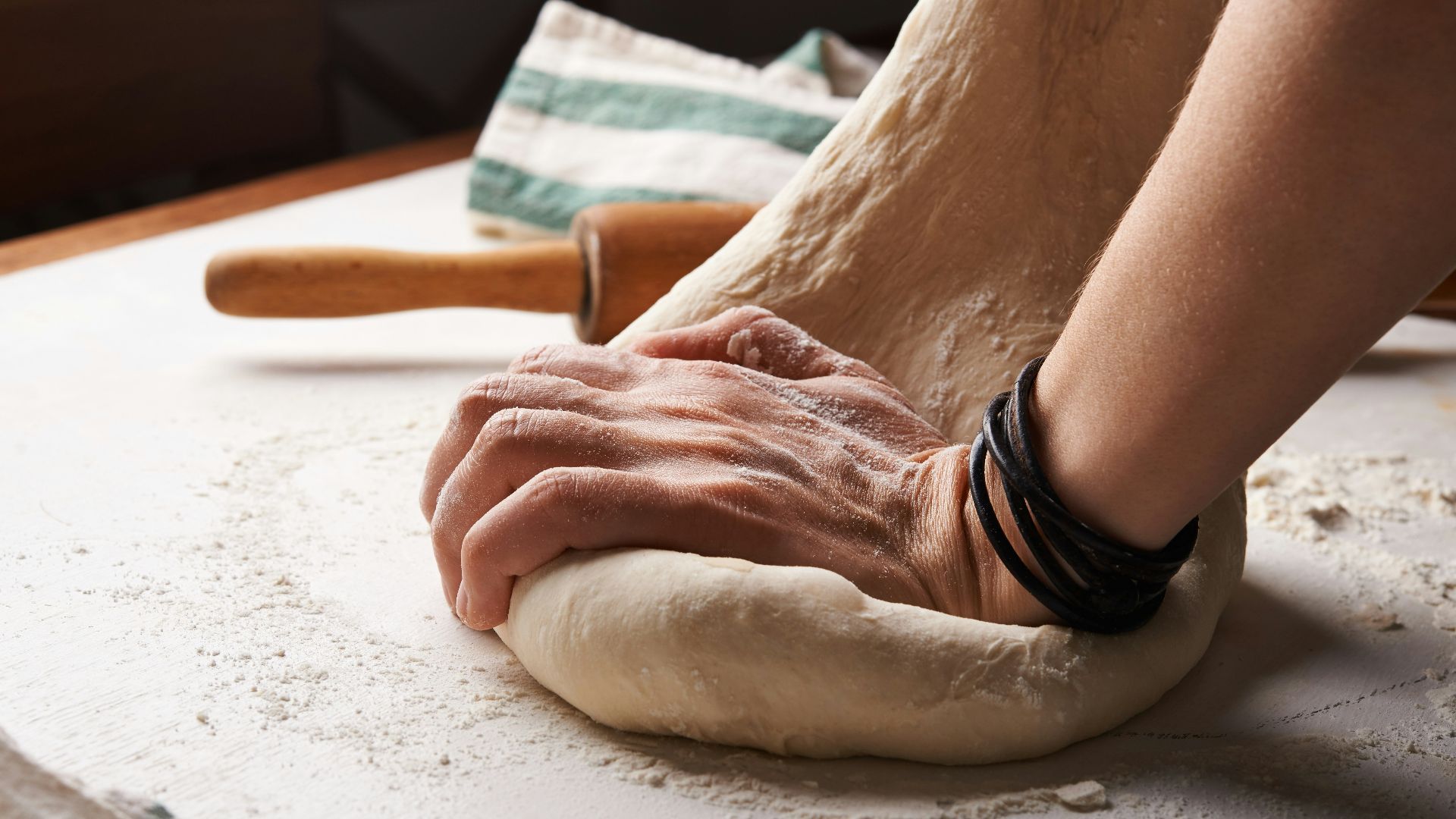 person making dough beside brown wooden rolling pin