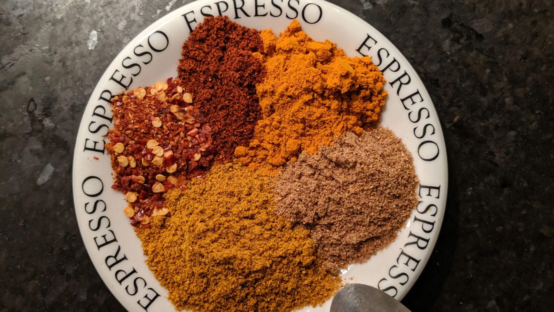 a plate of spices on a table with a spoon