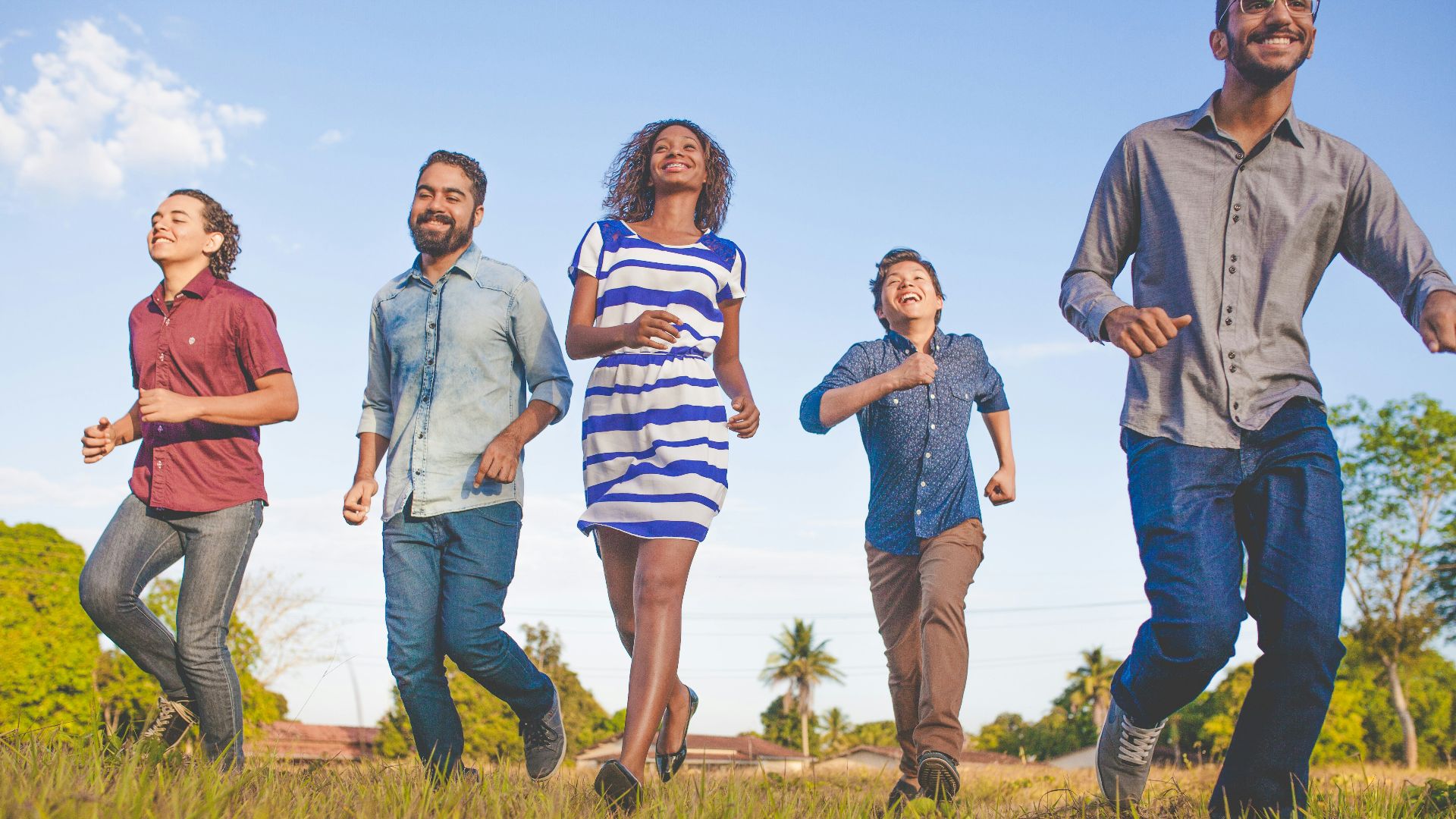 people running on grassfield under blue skies at daytime
