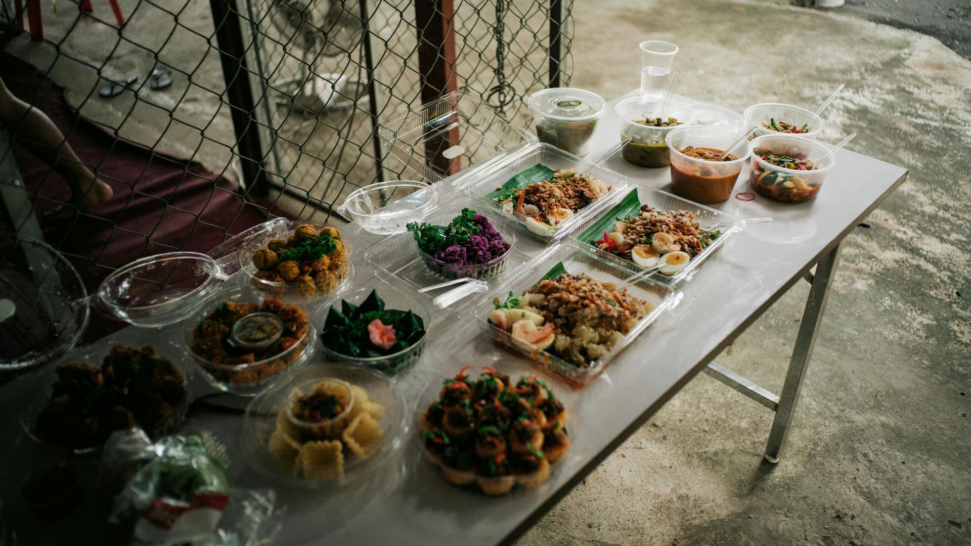 A table topped with lots of food next to a fence