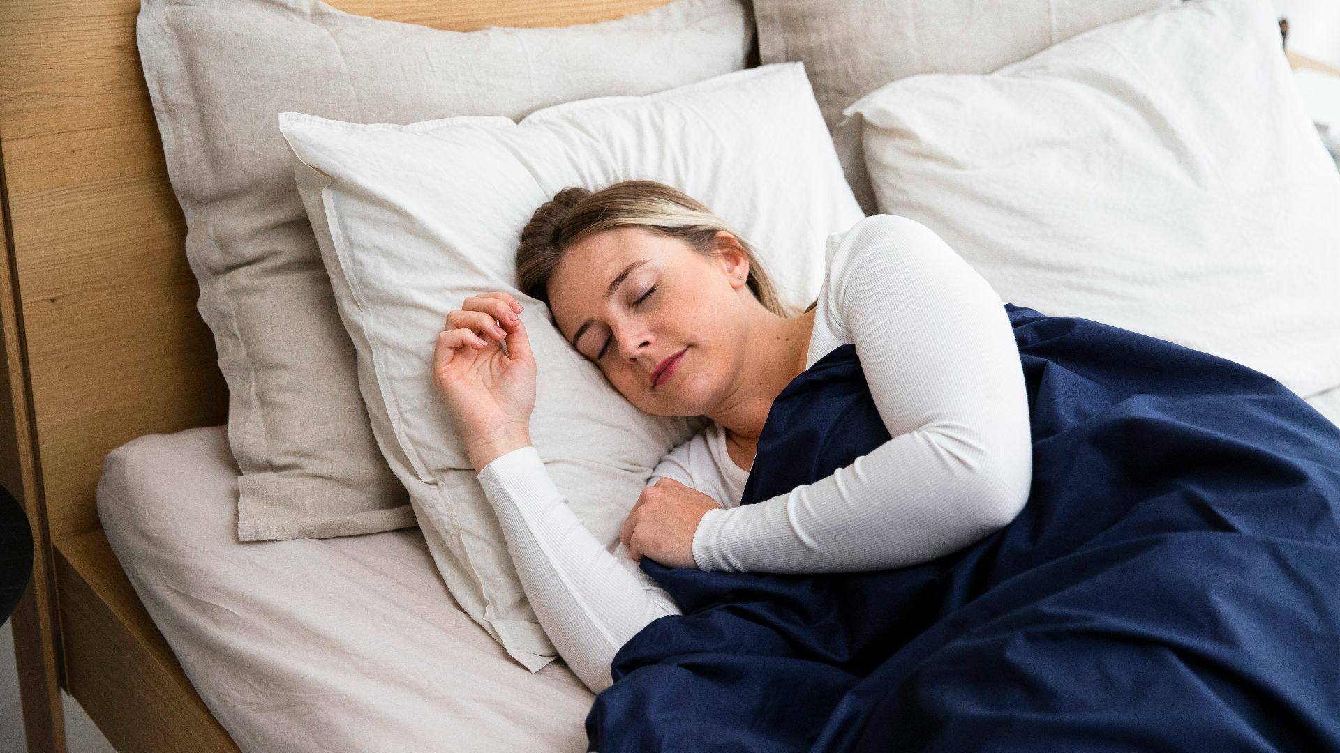 a woman sleeping on a bed with a blue blanket