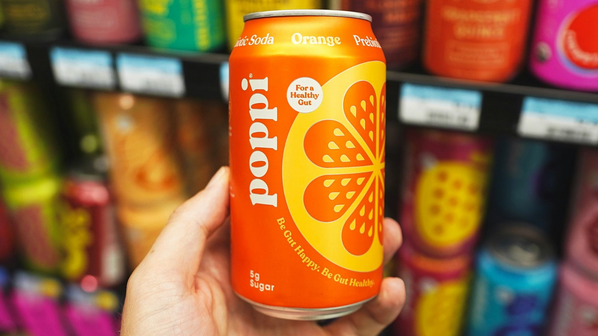 A hand holding a can of orange soda