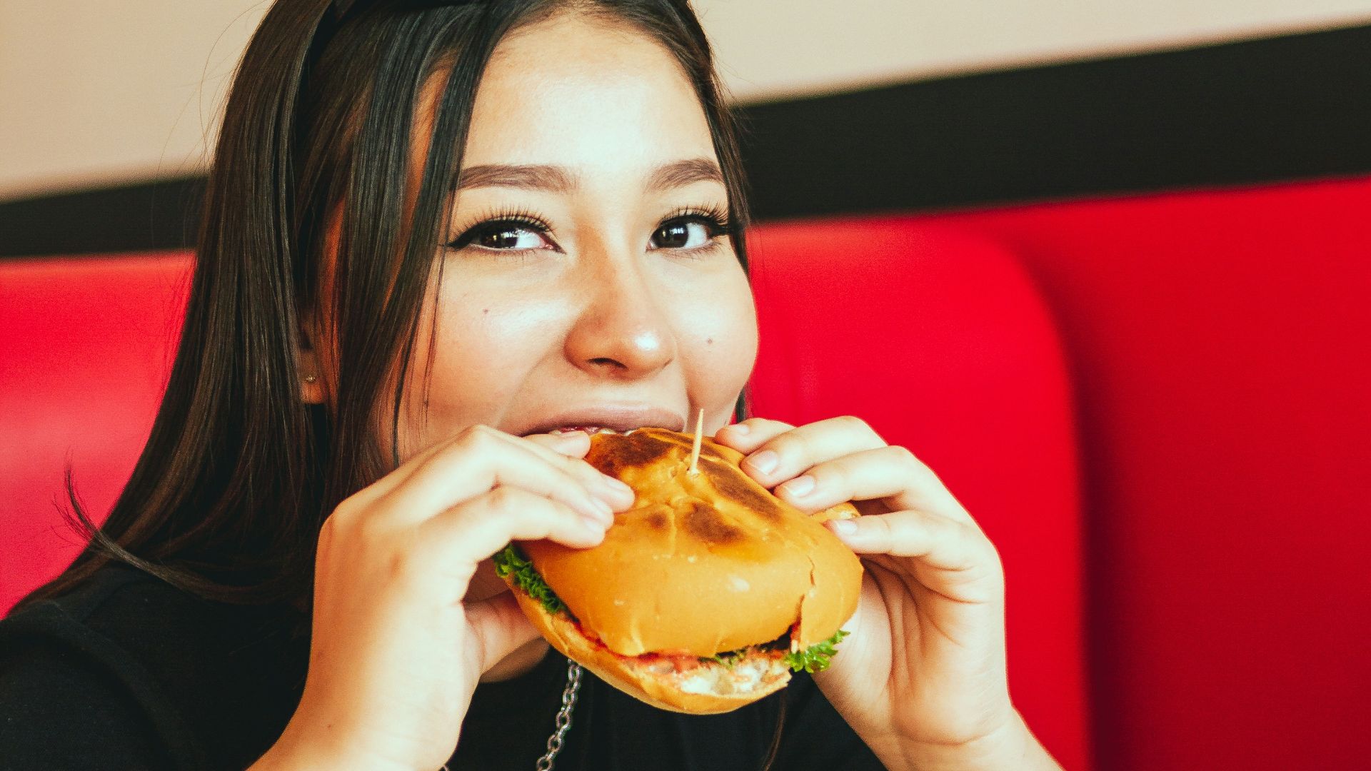 woman in black long sleeve shirt eating burger