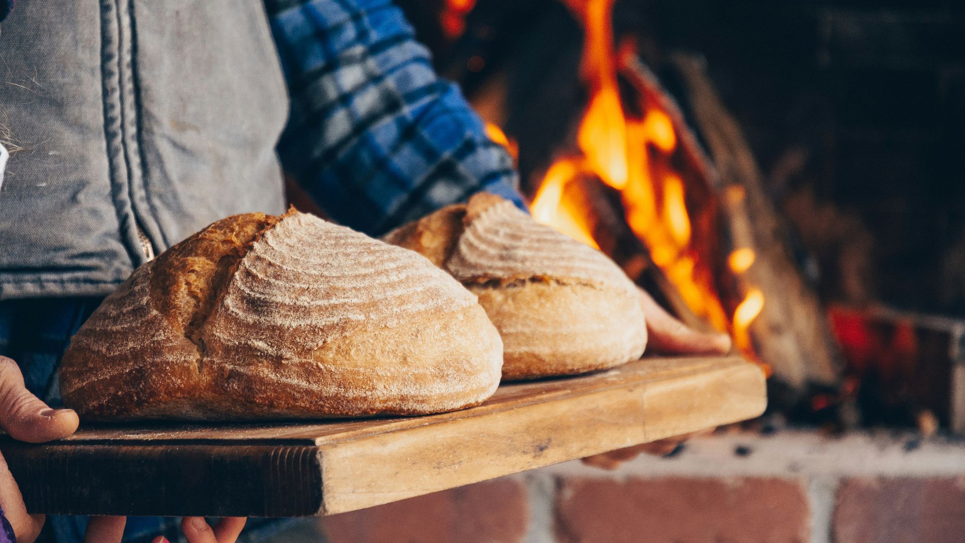 person in blue and white plaid long sleeve shirt holding bread