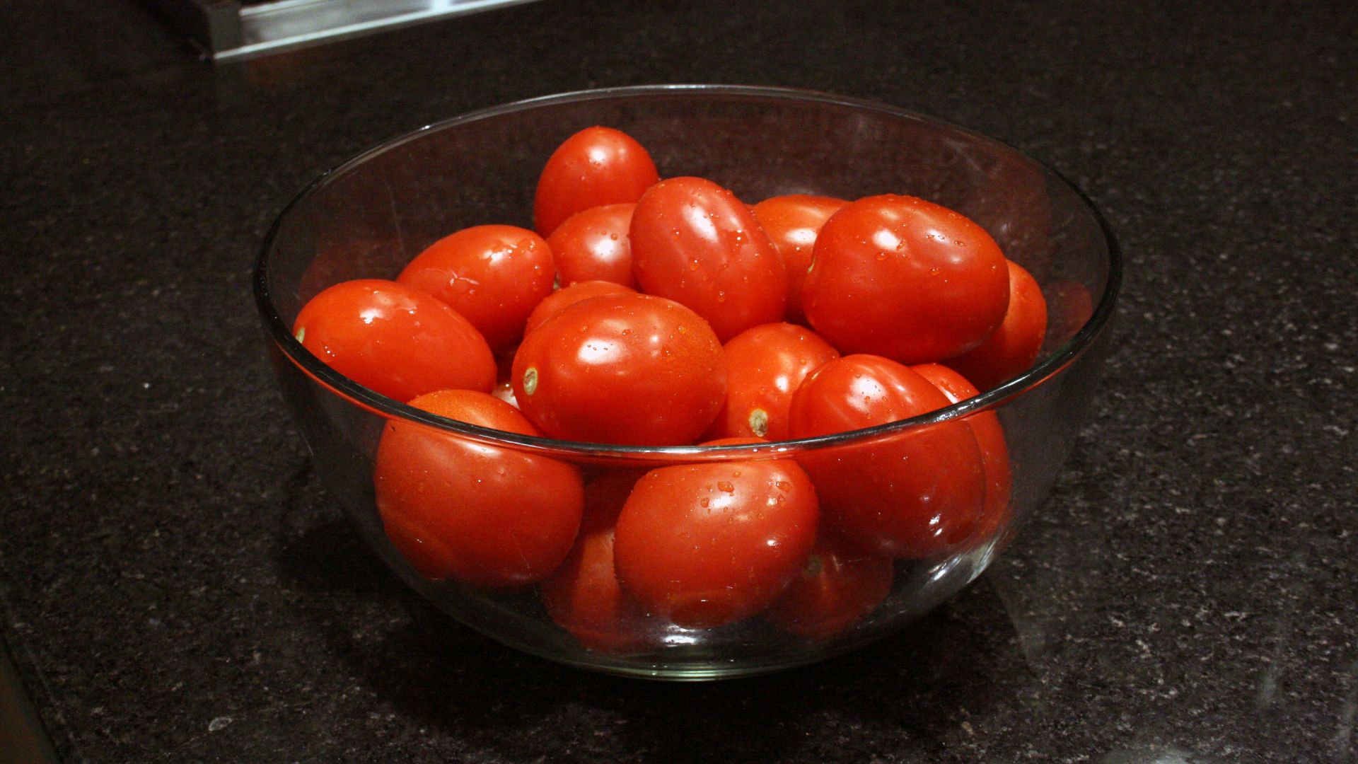 a bowl of tomatoes sitting on a counter top