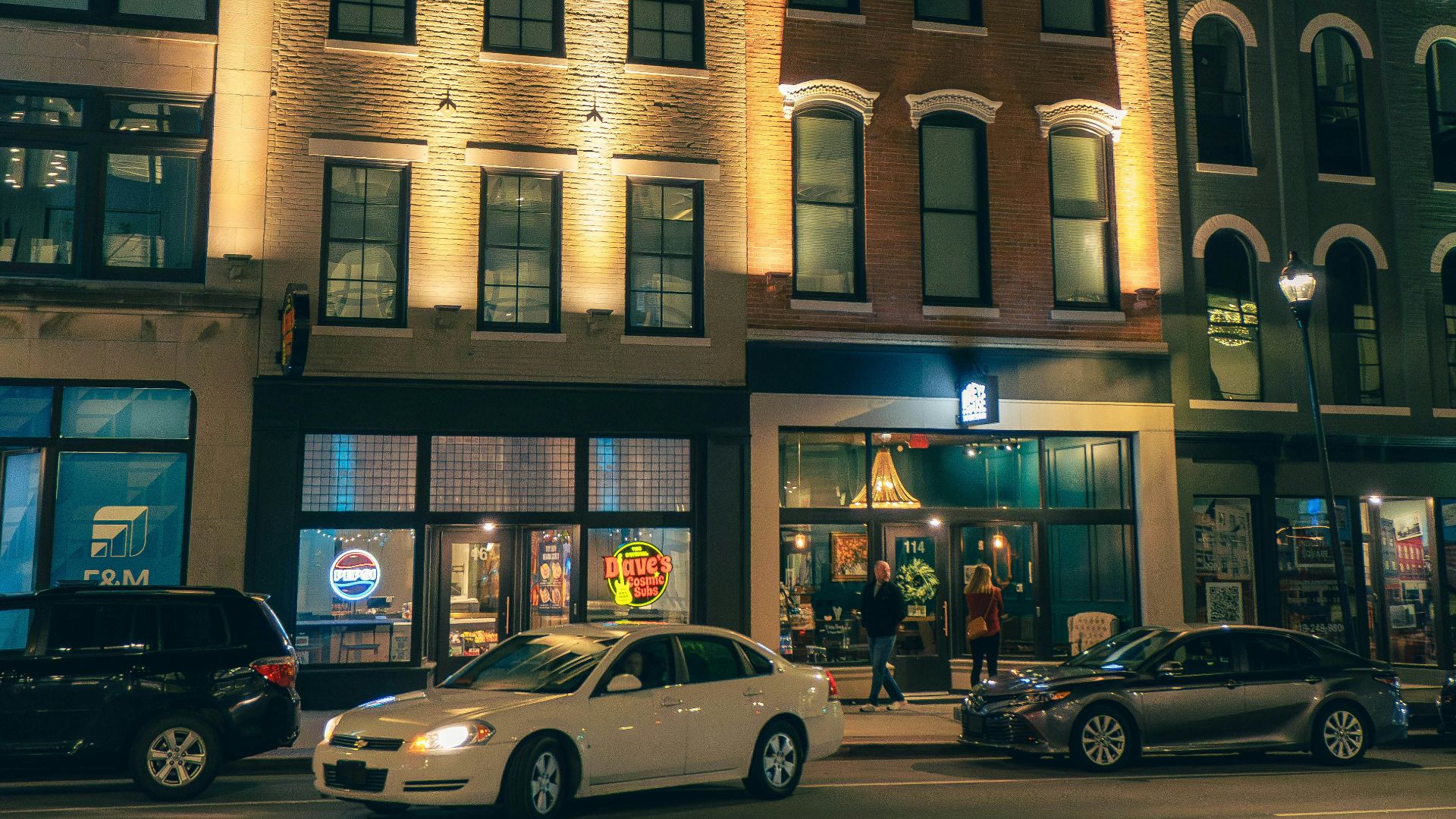 Night scene of a street with lit buildings.
