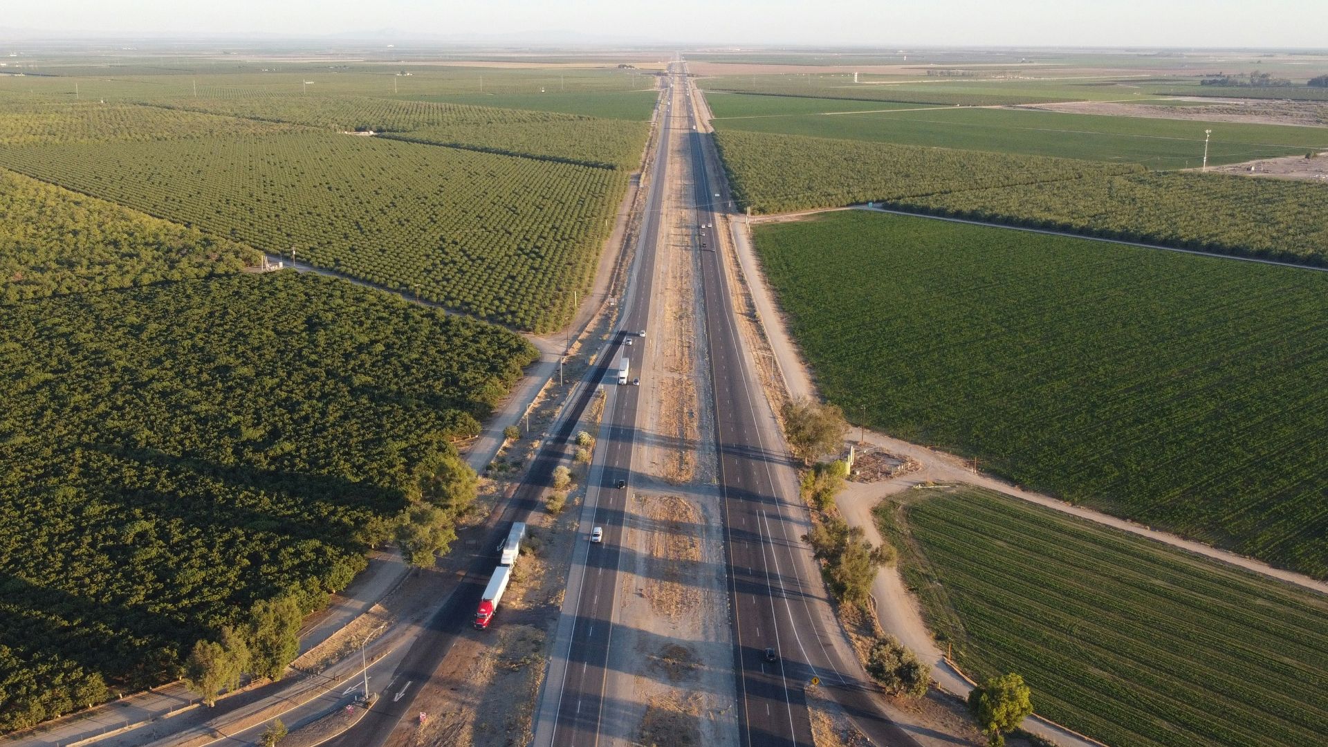 gray asphalt road between green grass field during daytime