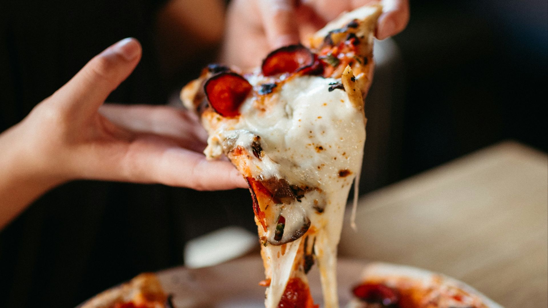 a person takes a slice of pizza