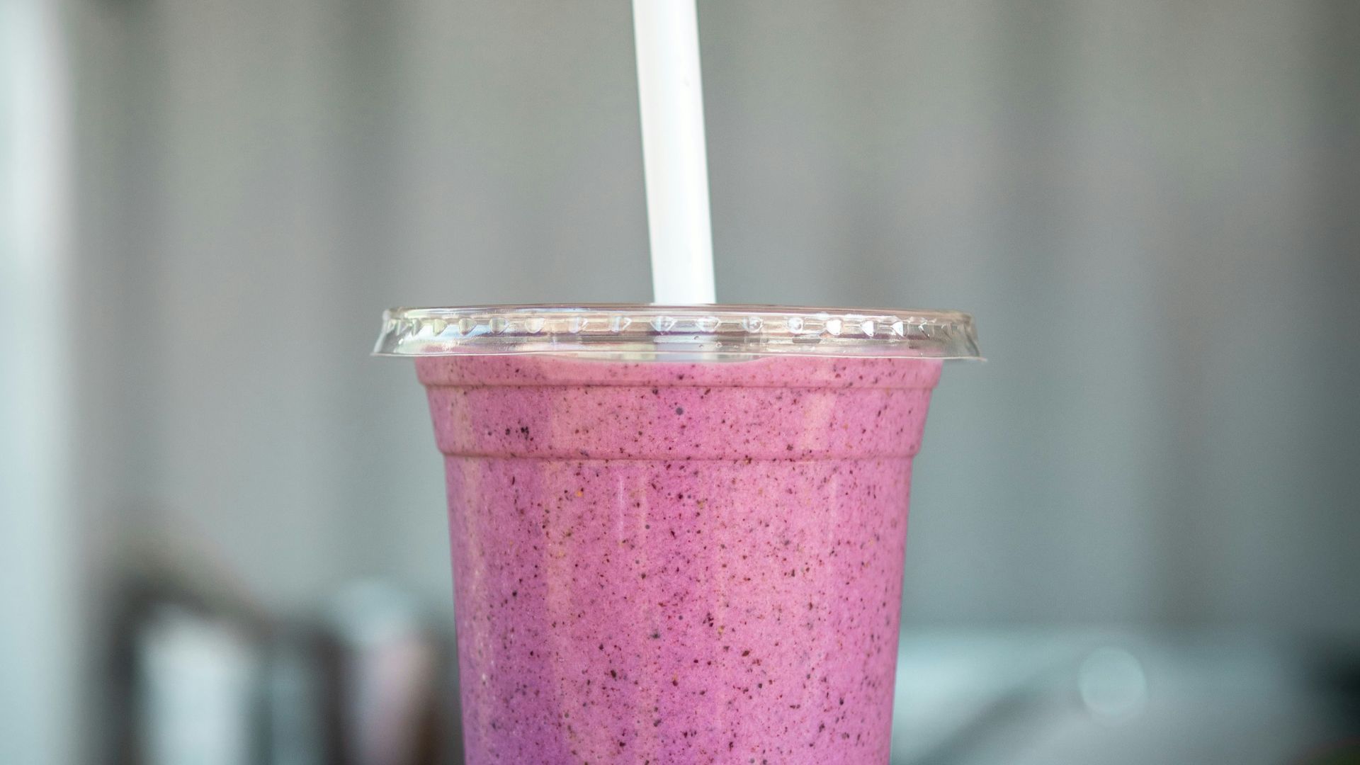 clear cup with straw on beige wooden surface