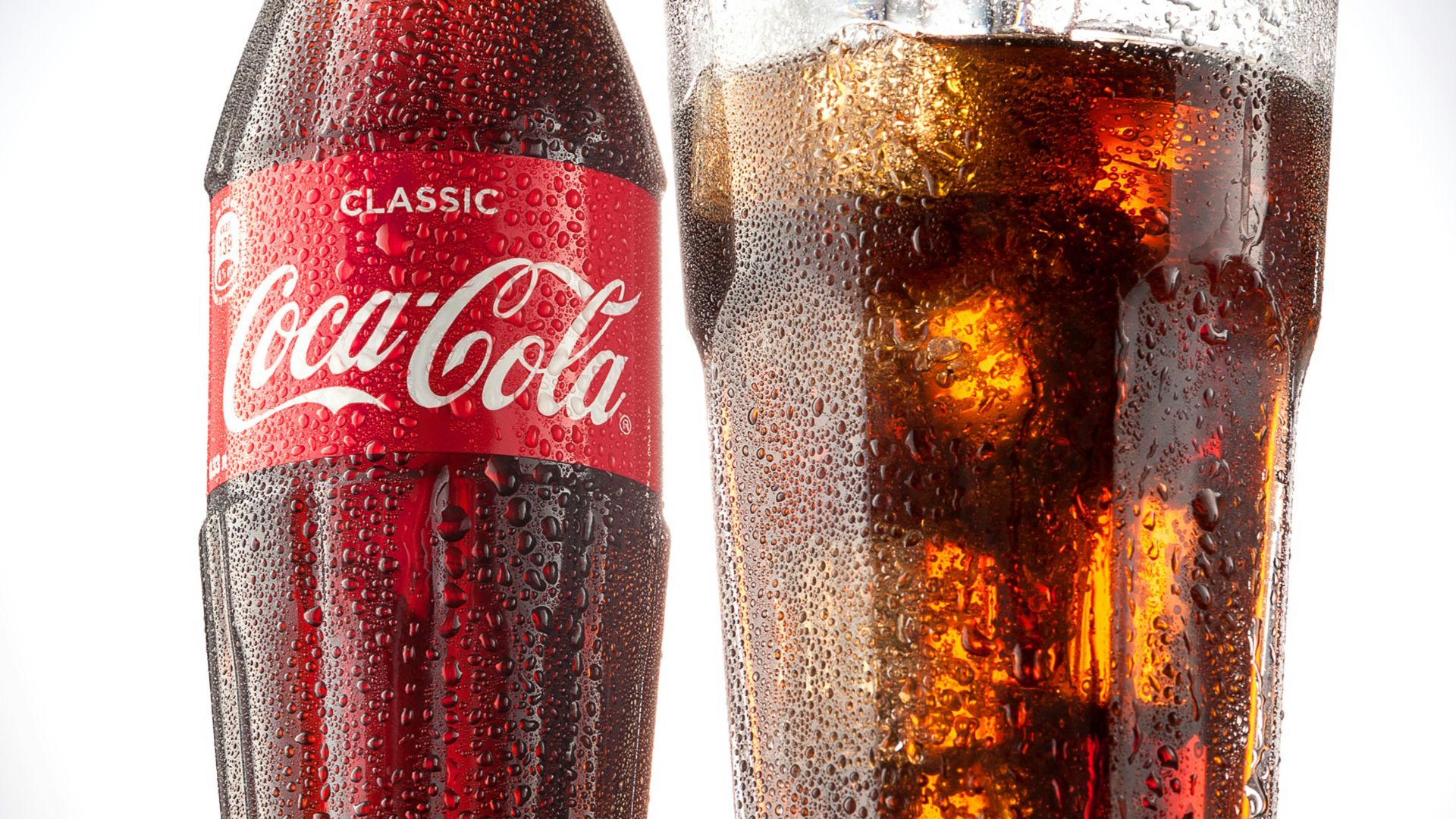 coca cola bottle beside drinking glass