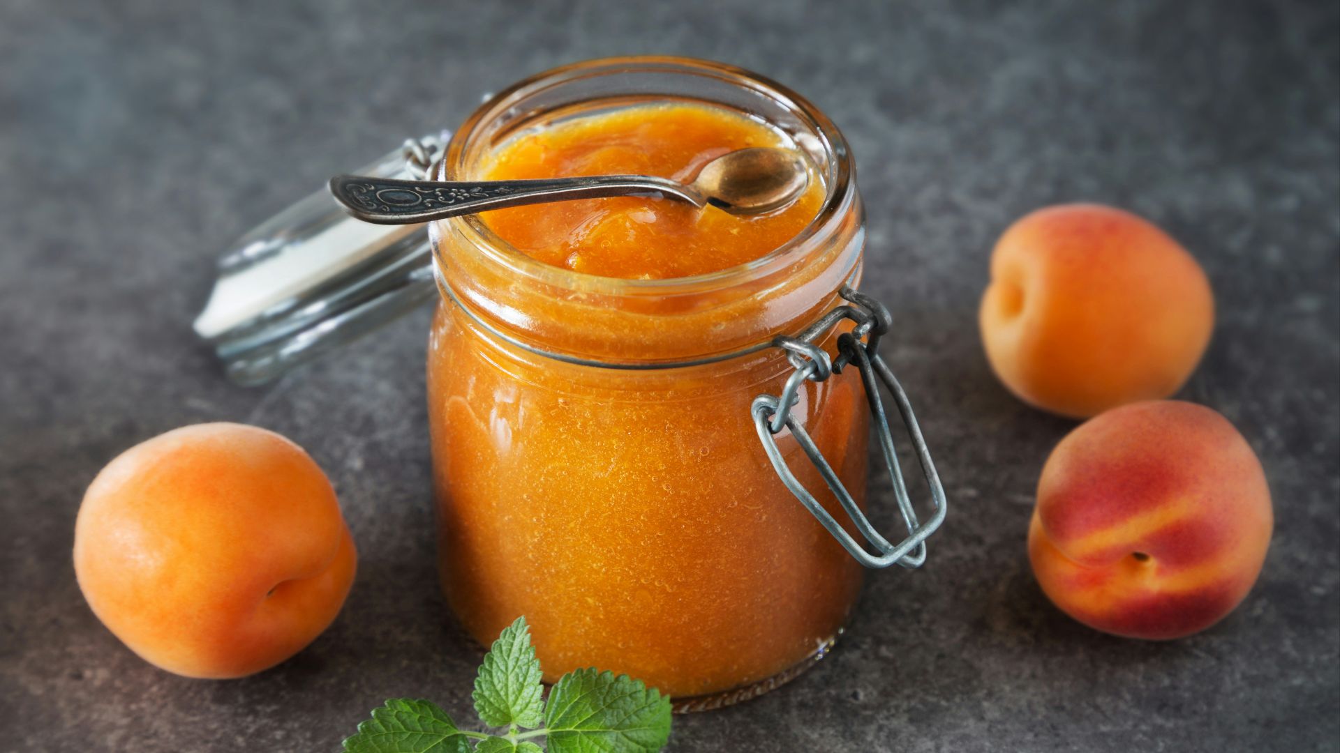 a jar of peach jam next to some peaches