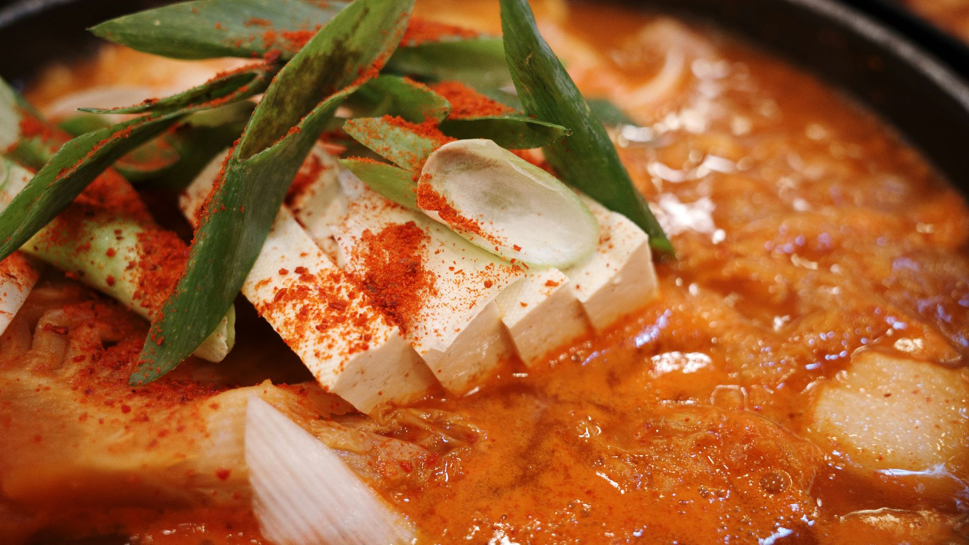Close-up of spicy korean stew with tofu and scallions