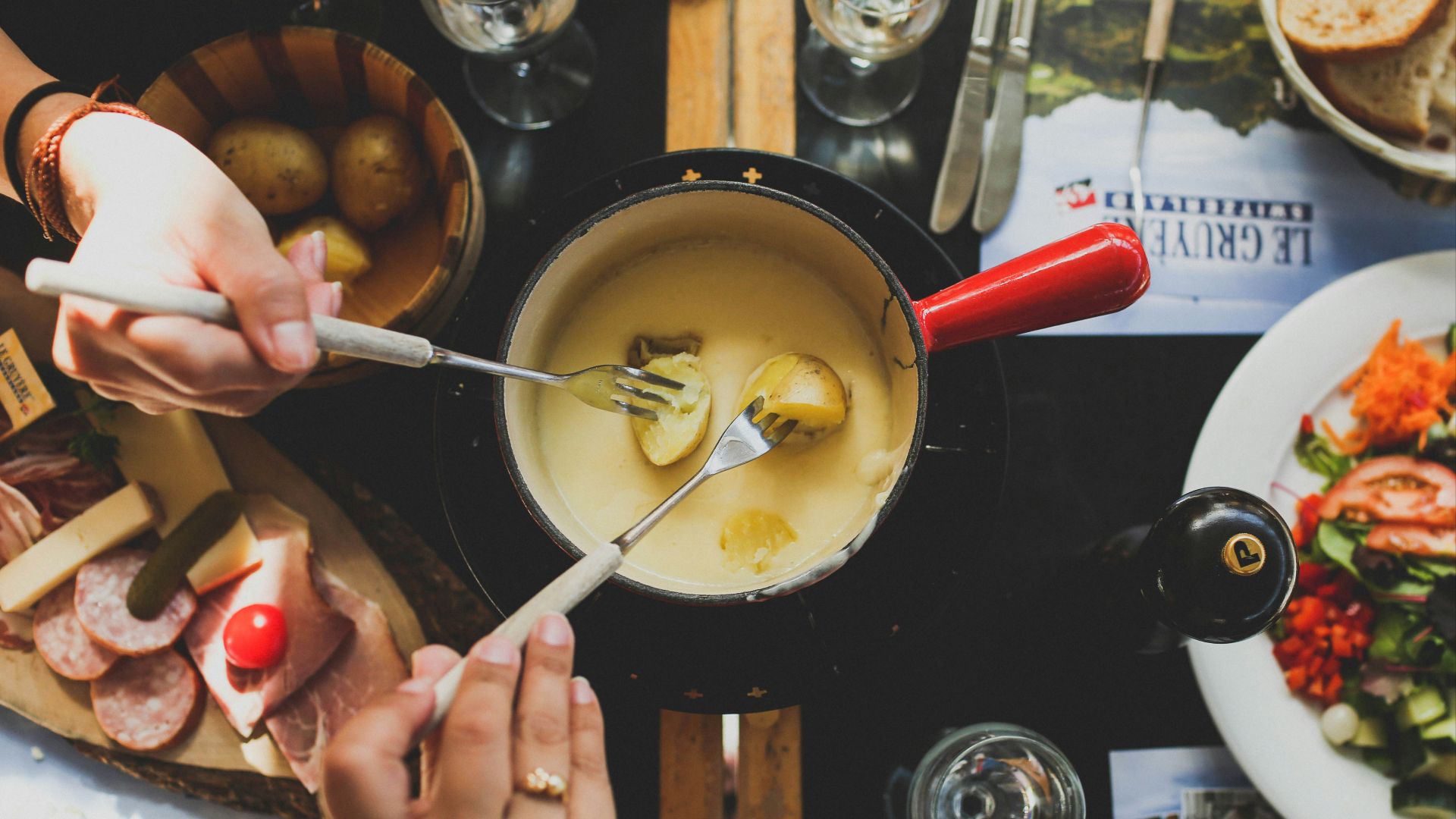 two person holding fork dipping food on sauce