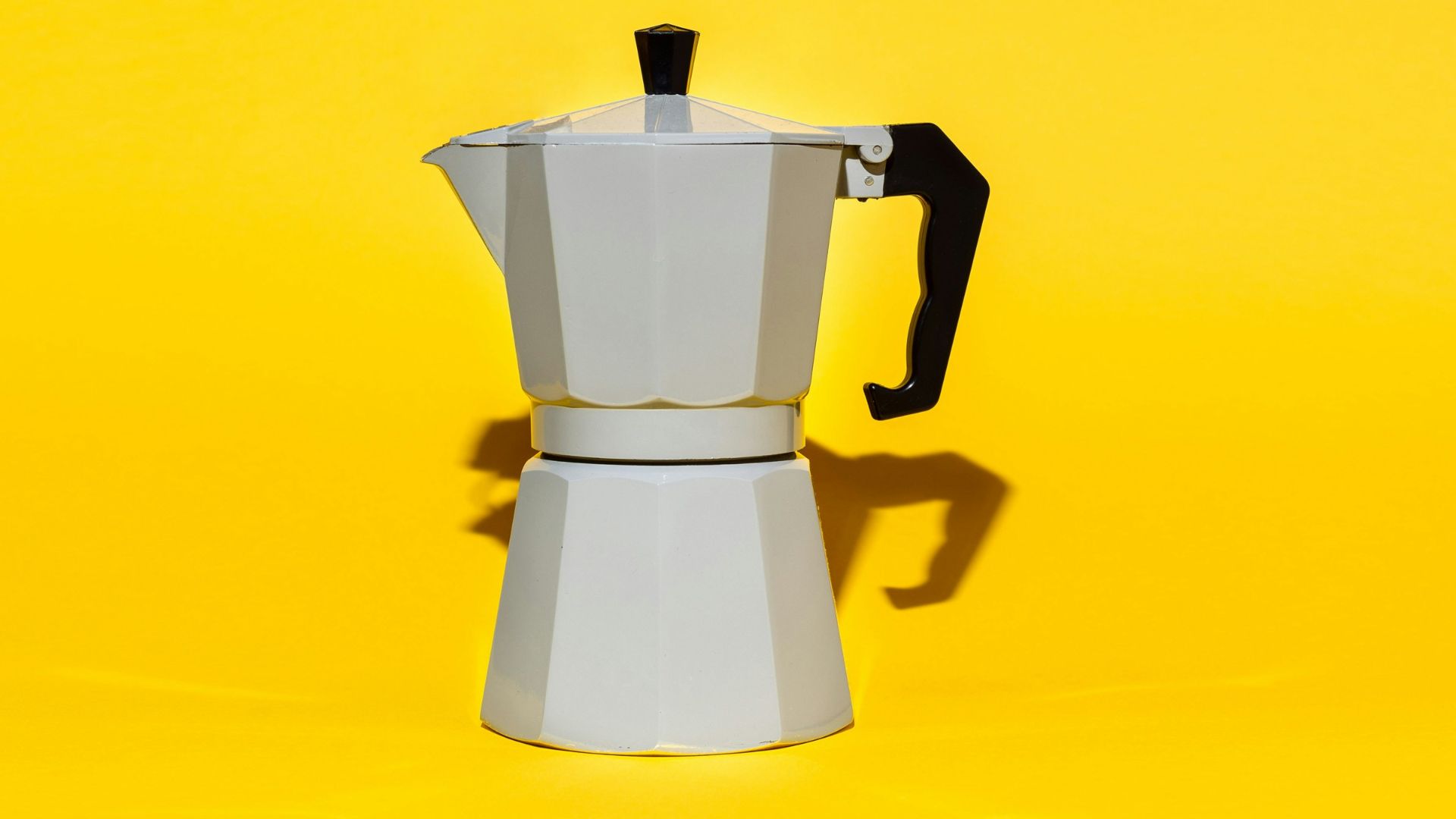 a stove top coffee maker on a yellow background