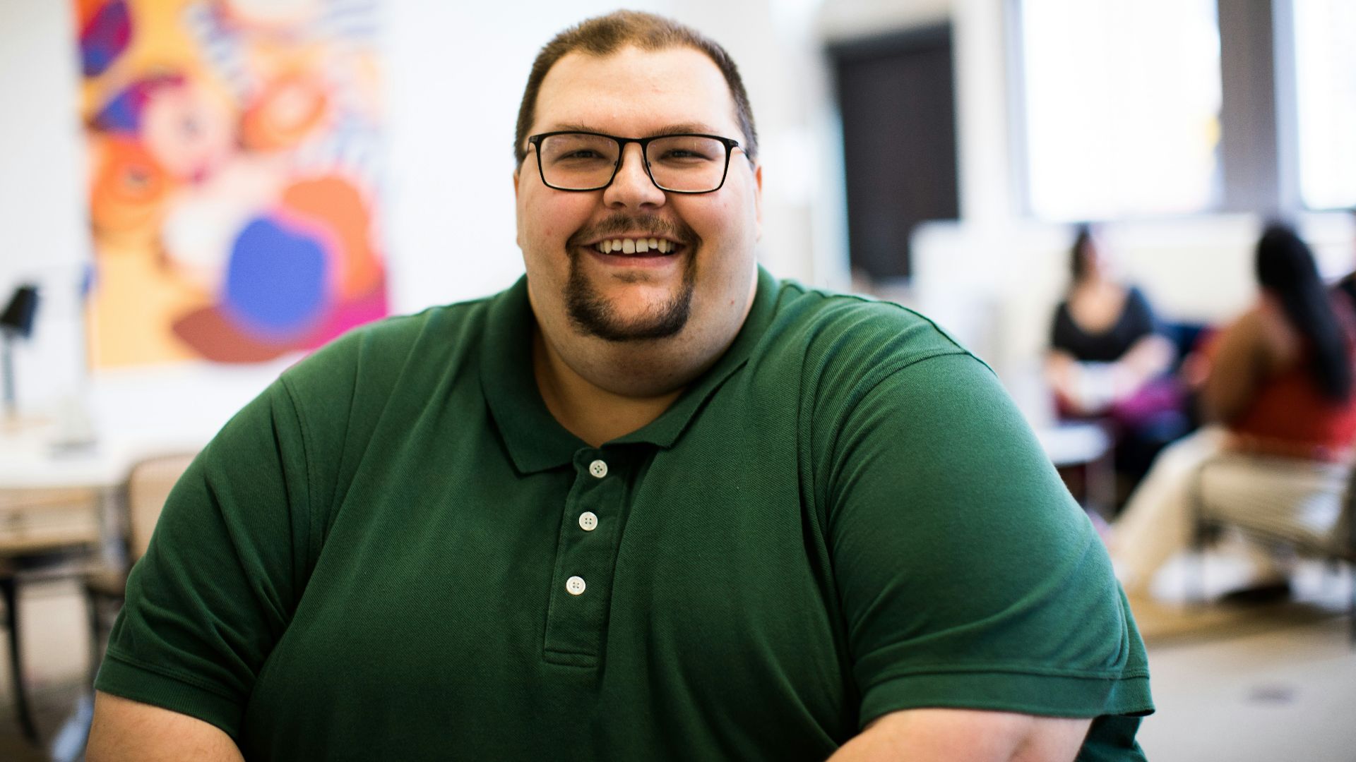 man sitting down wearing green polo shirt