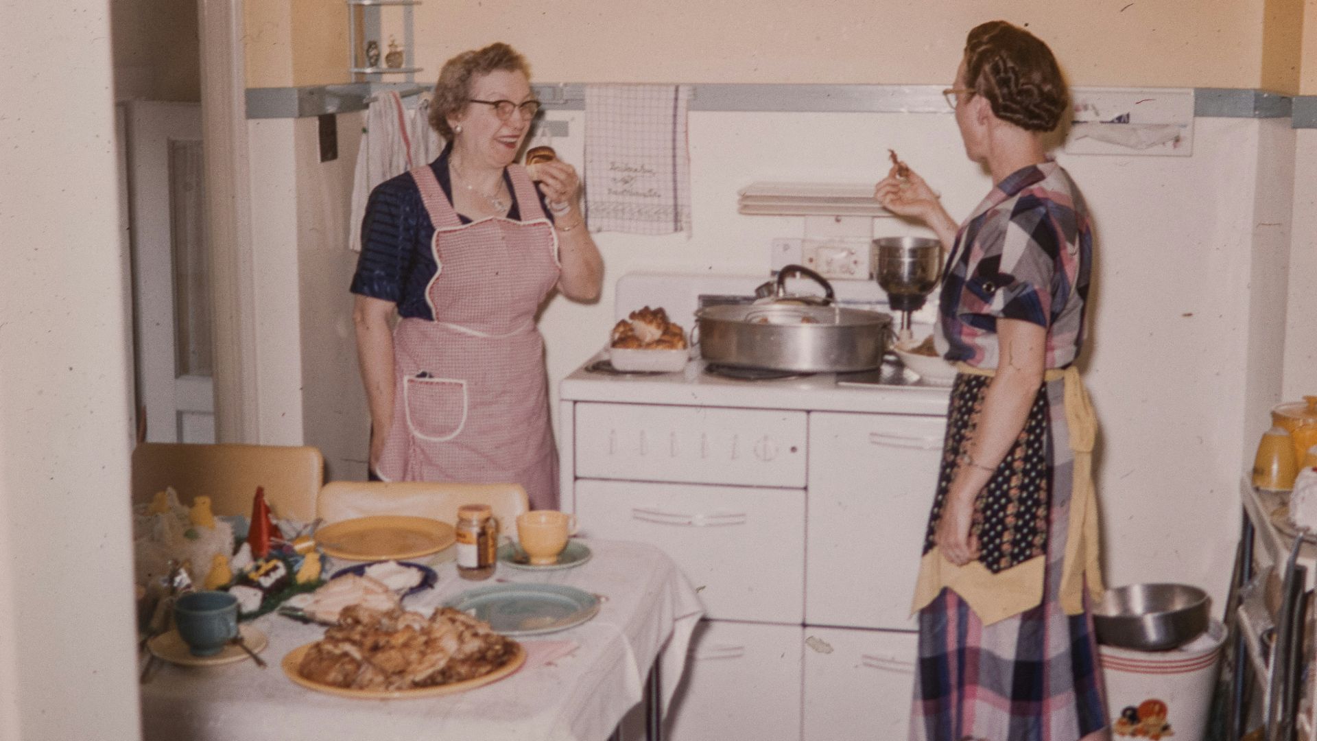 a couple of women standing in a kitchen