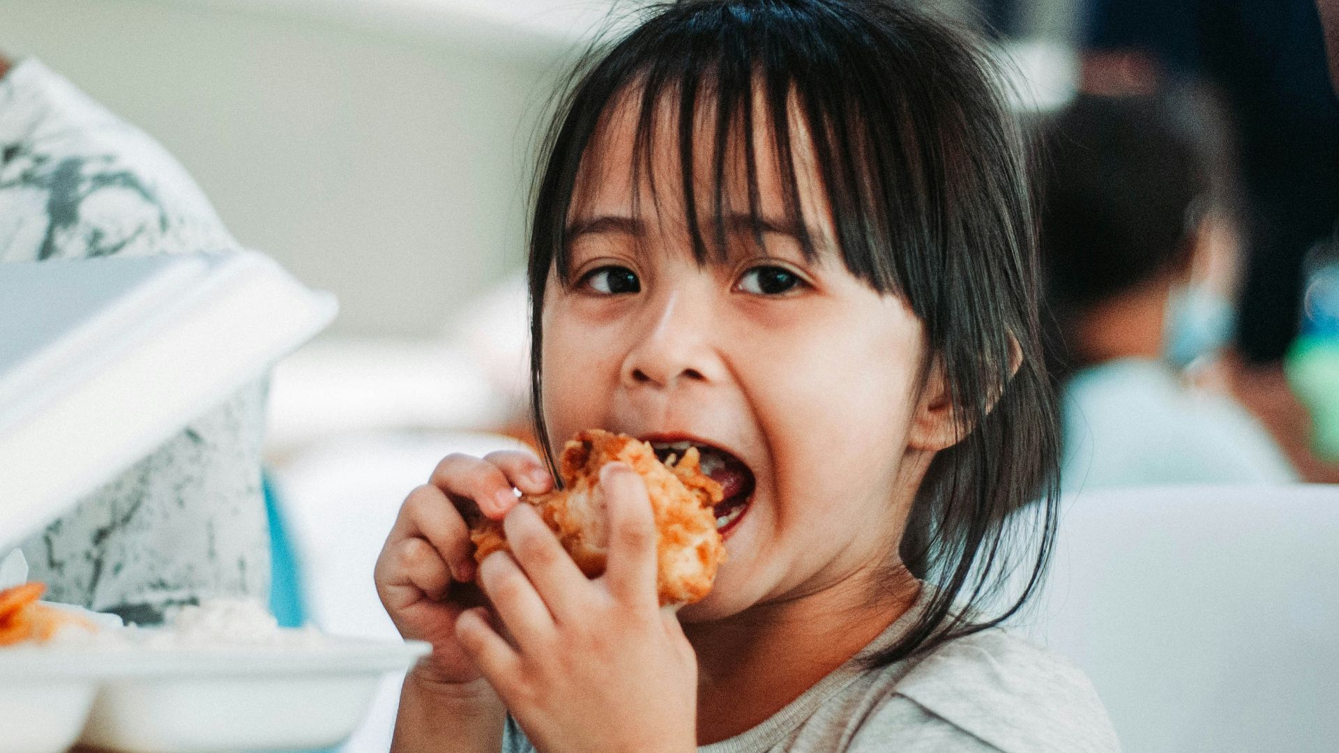 girl biting a good by table at daytime
