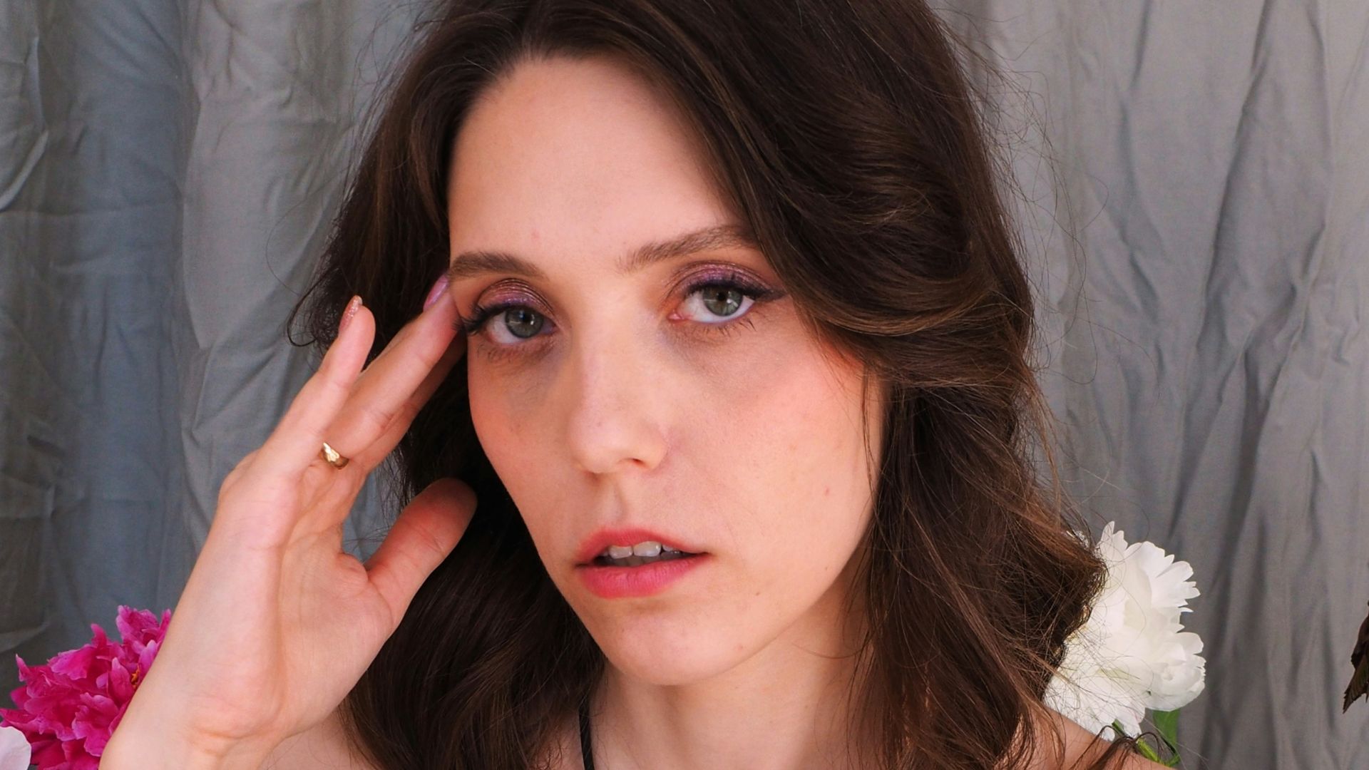A woman in a blue dress holding her hand up to her face
