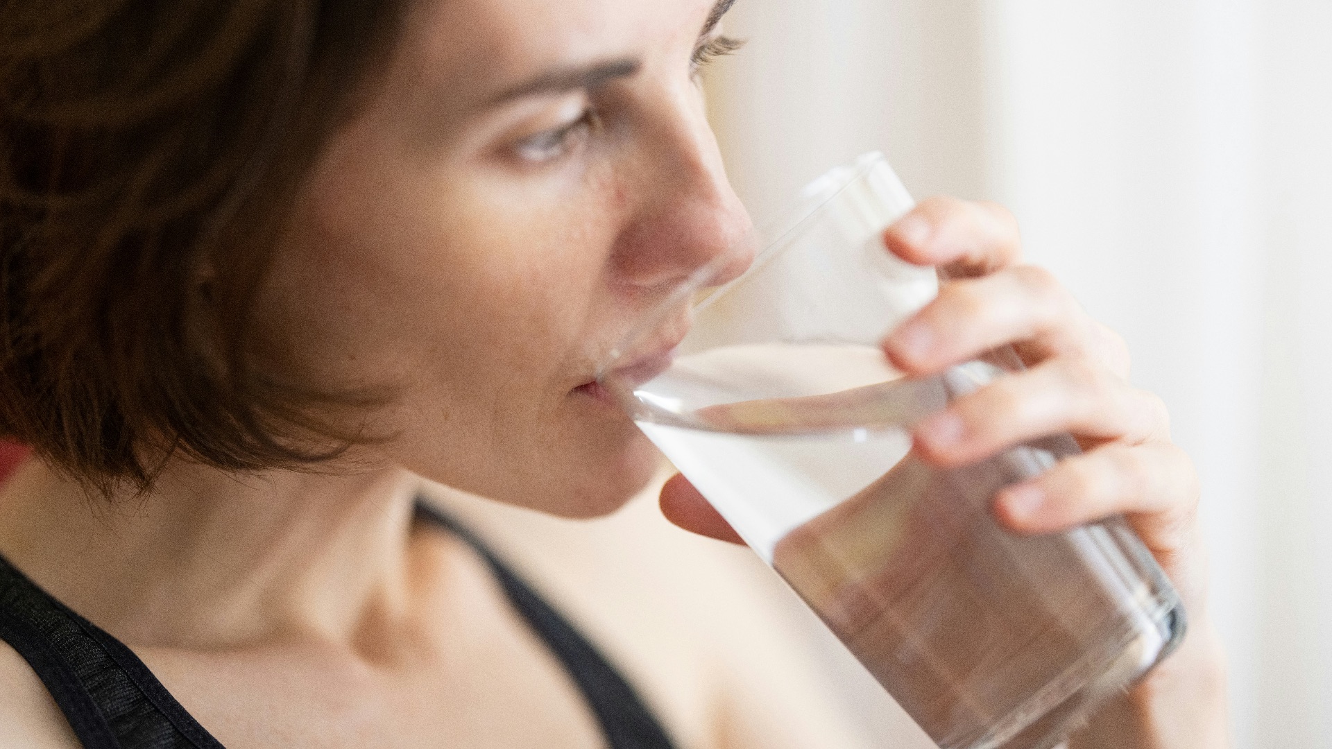 woman in black tank top drinking water