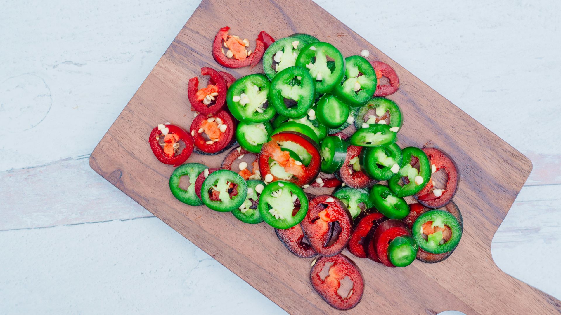 a wooden cutting board topped with green and red peppers