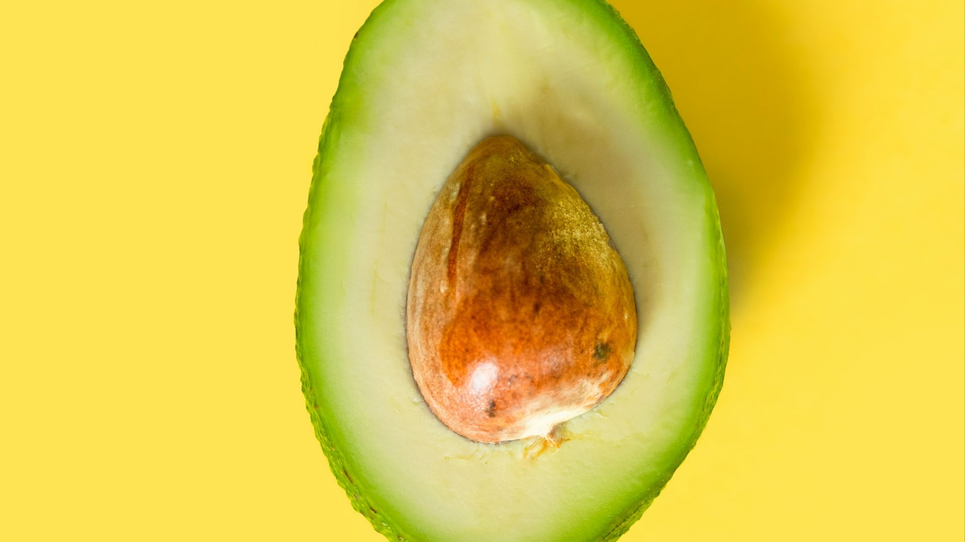 an avocado cut in half on a yellow background