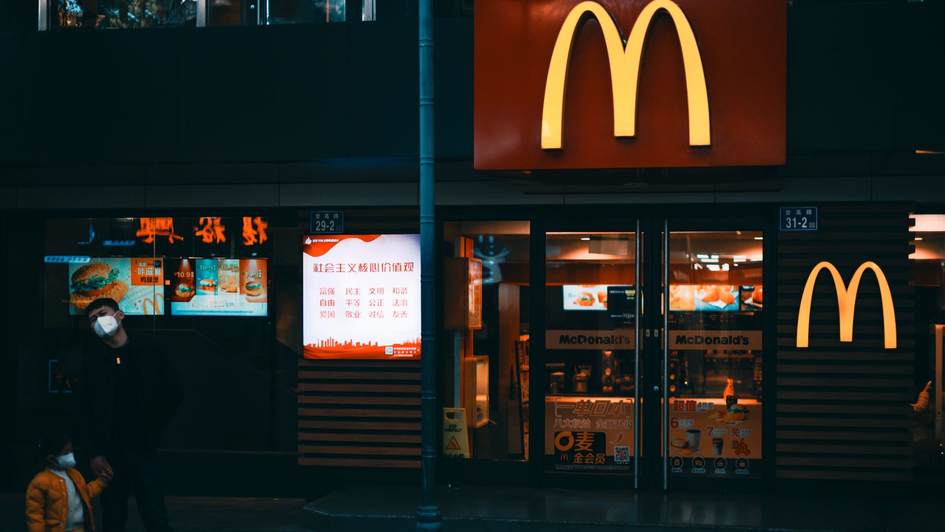 a man standing on a sidewalk in front of a mcdonald's
