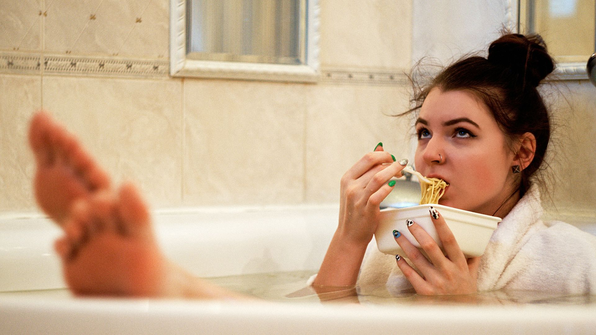 girl in bathtub holding white ceramic mug