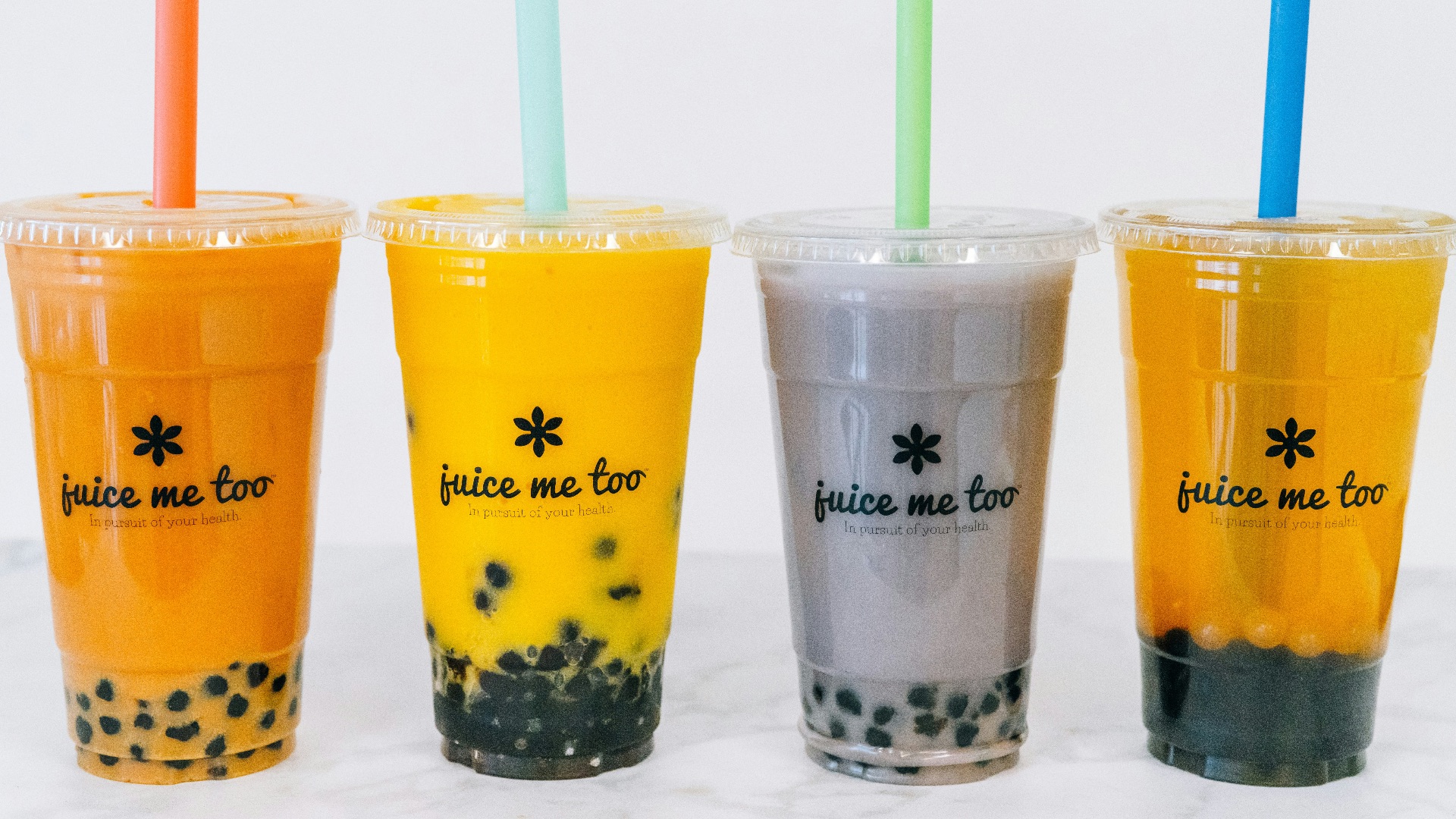 Four colorful boba teas with straws.