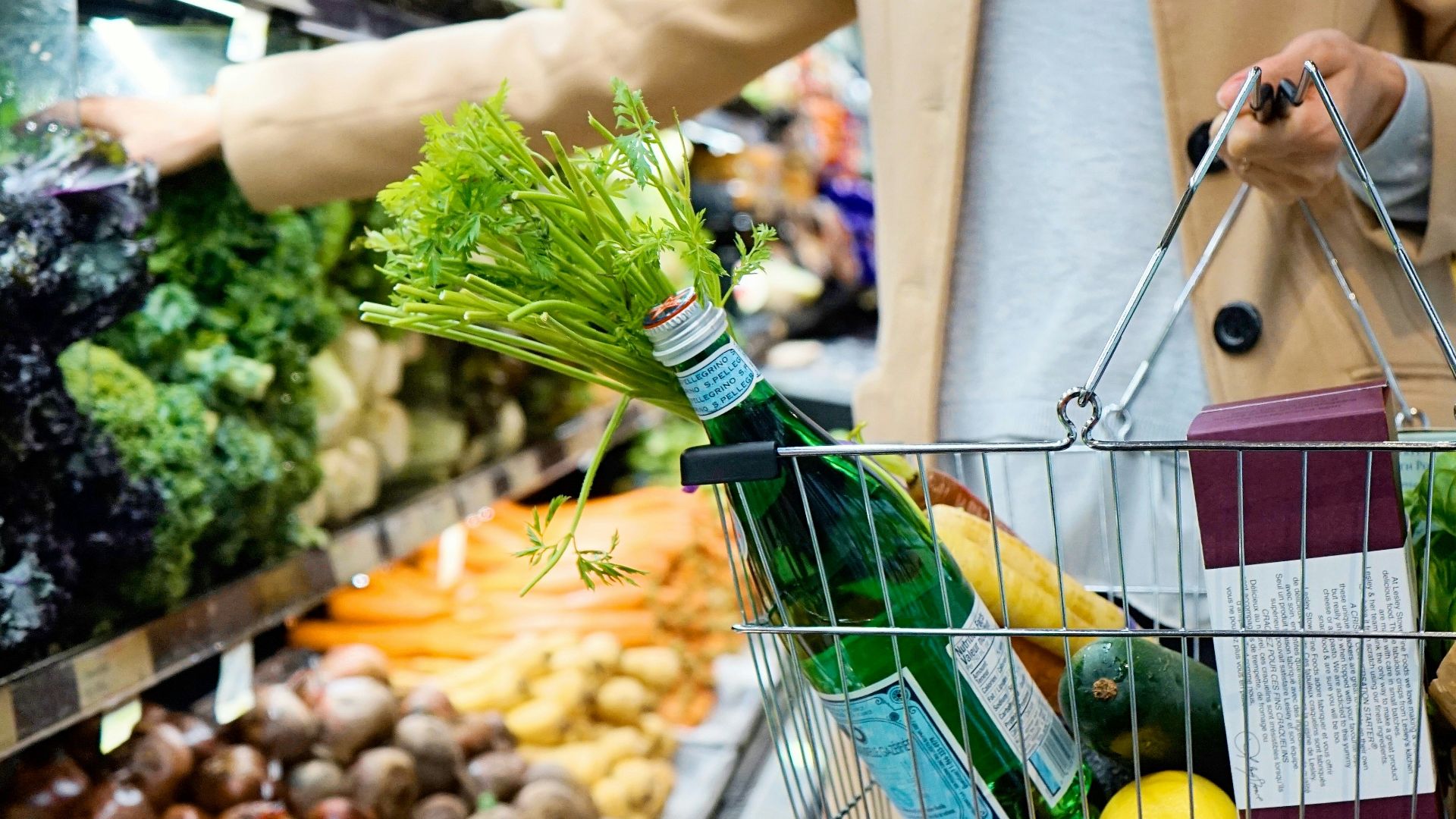 woman in white coat holding green shopping cart