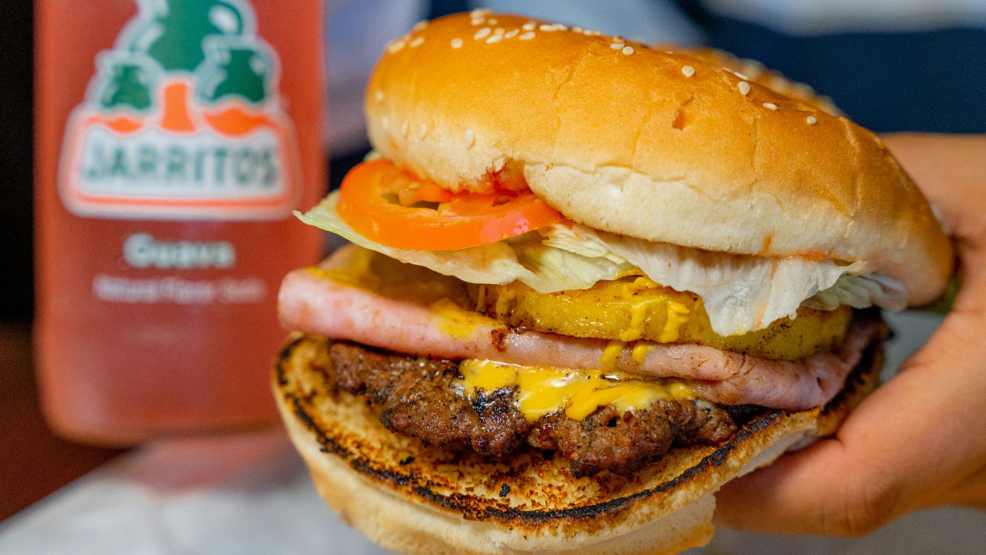 a person holding a hamburger and a bottle of juice
