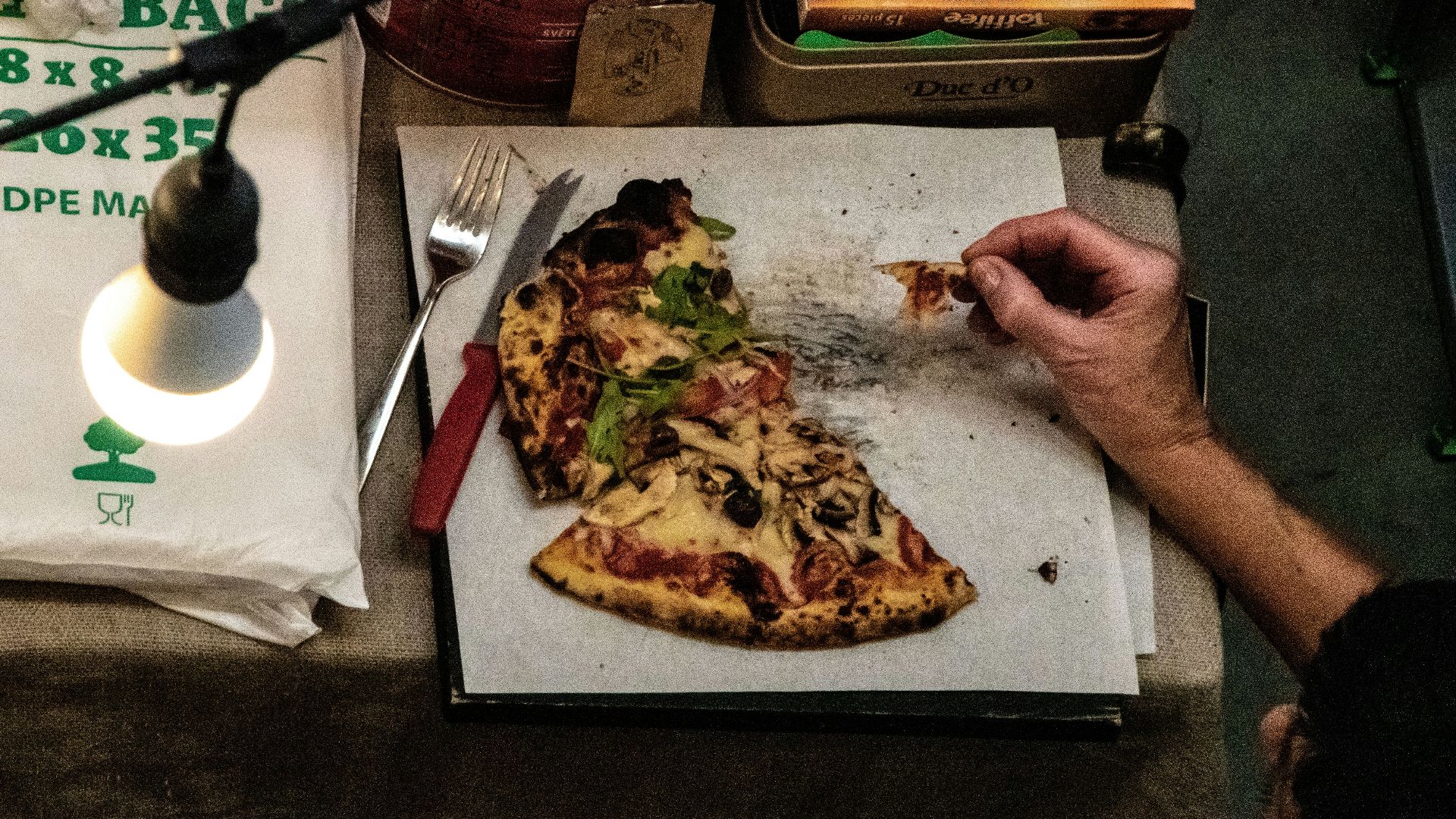 a person eating a slice of pizza from a box