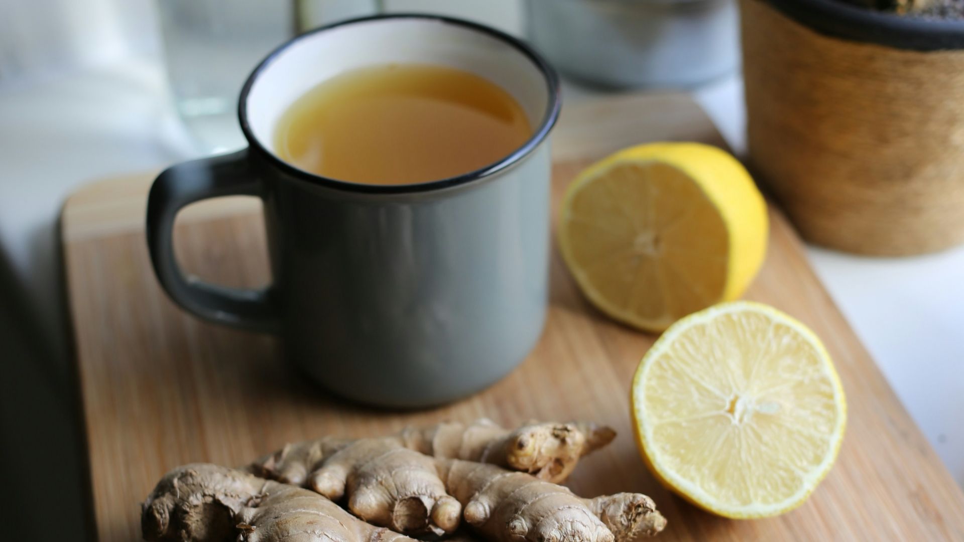 a wooden cutting board topped with sliced lemons and ginger