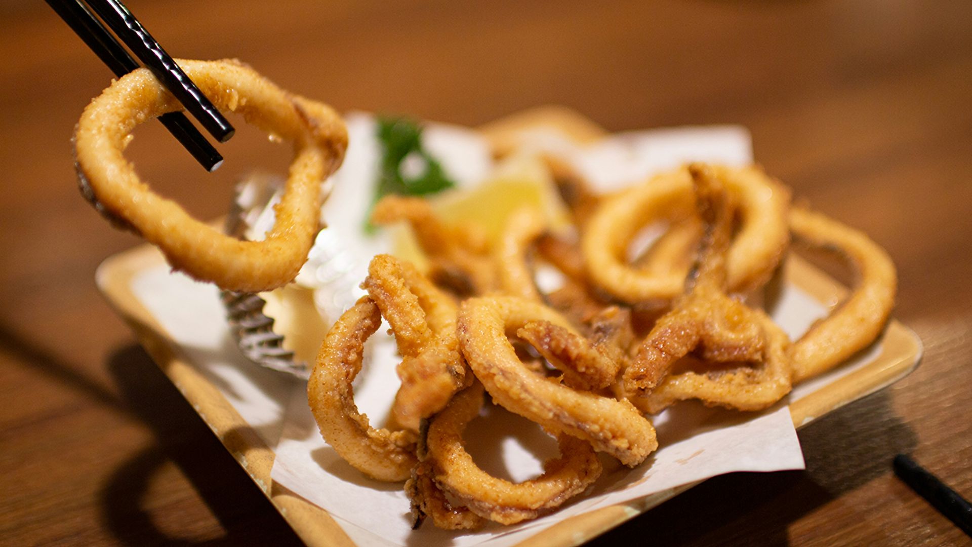 Fried calamari rings are being picked up with chopsticks.