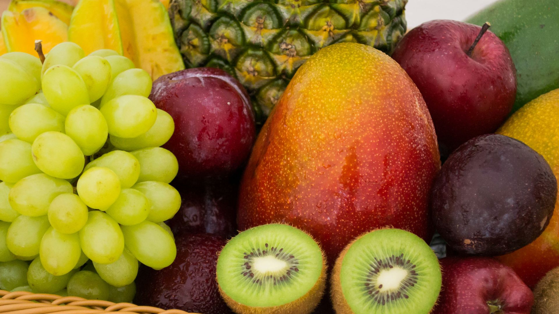 red apple fruit beside green apple and yellow fruit on brown woven basket