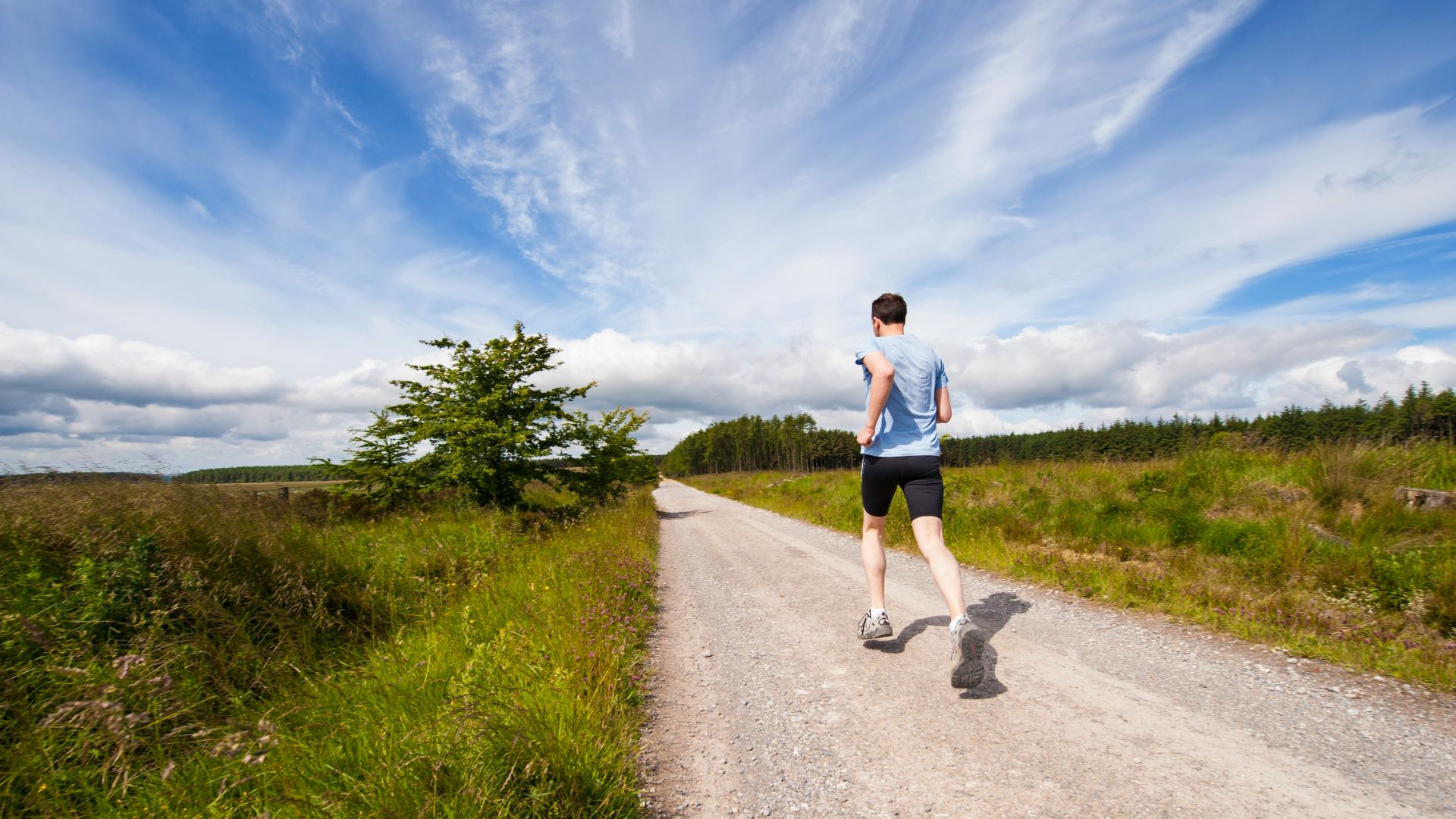 man running on road near grass field