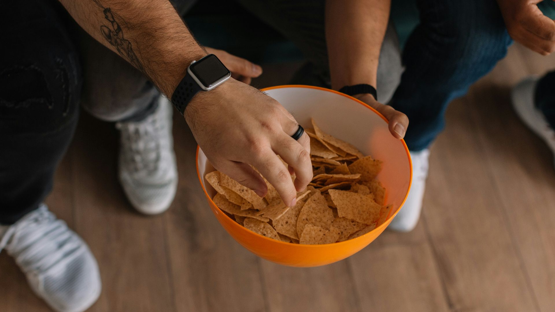 person holding orange bowl with potato chips