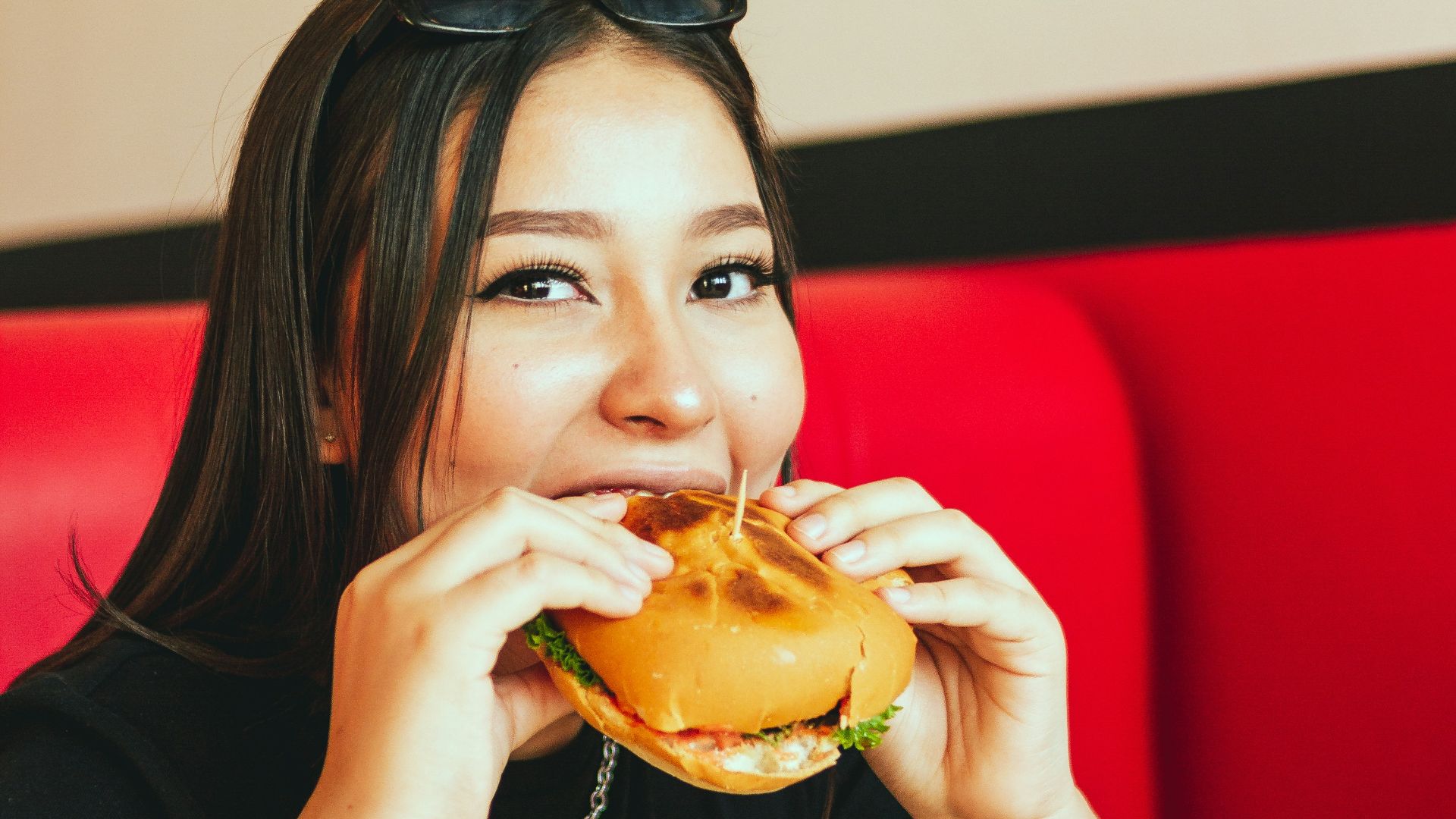 woman in black long sleeve shirt eating burger