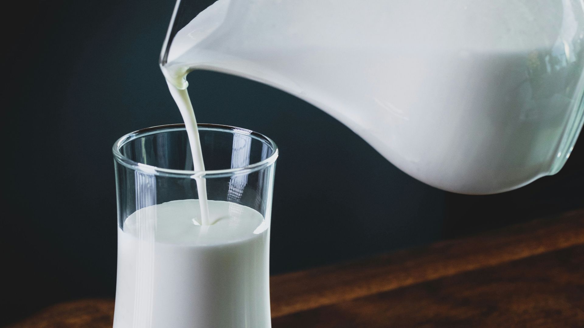 person pours milk into glass