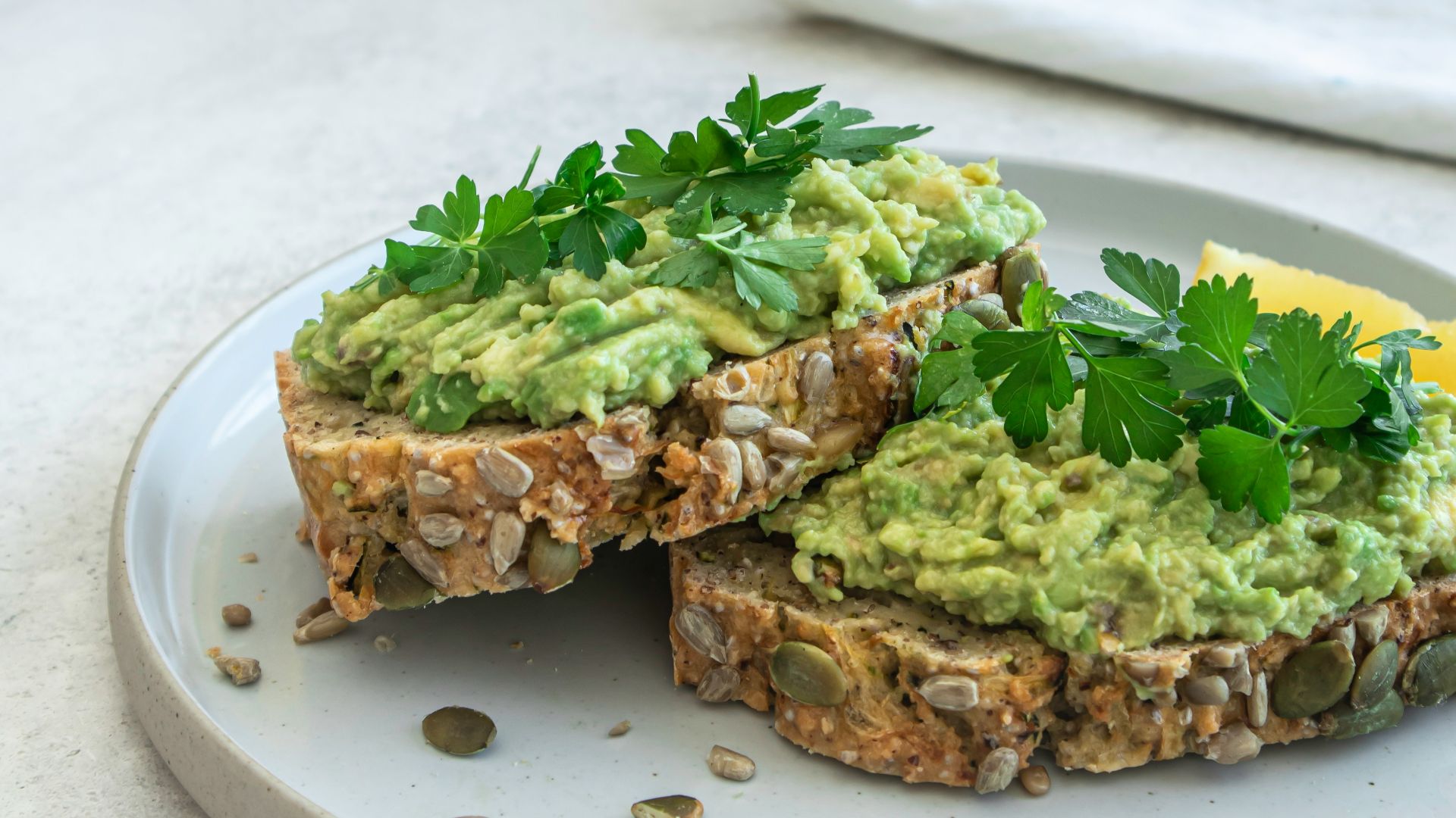 a white plate topped with a sandwich covered in guacamole