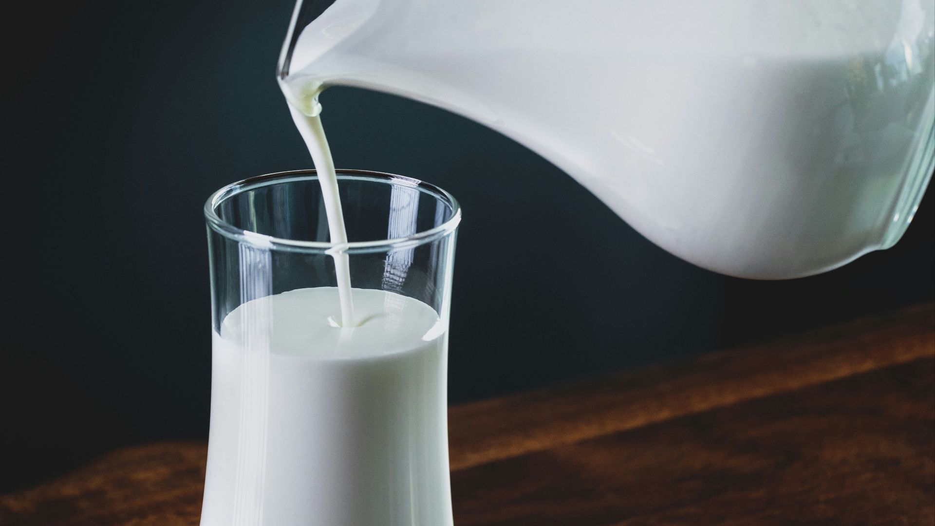 person pours milk into glass