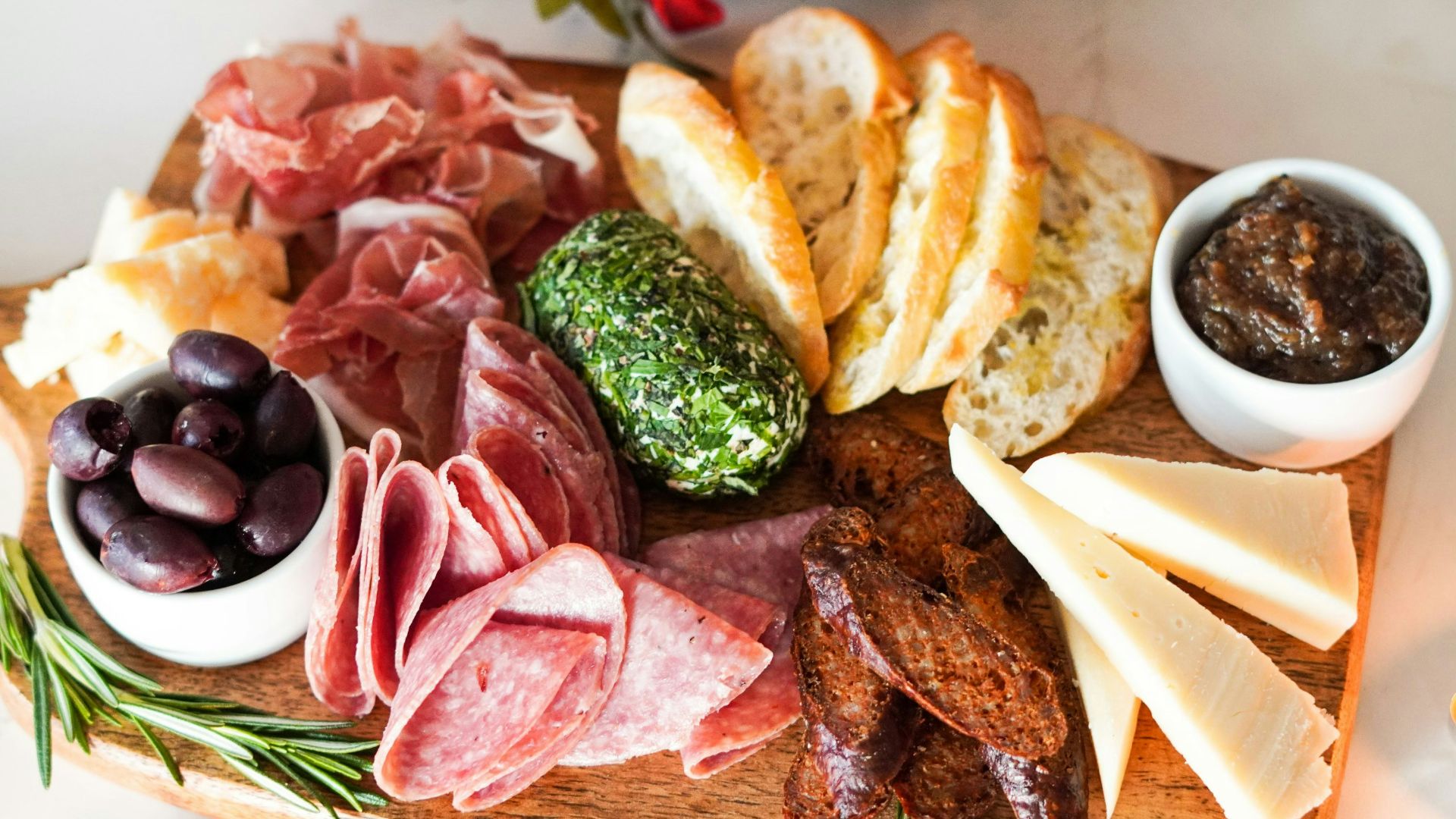 sliced meat with vegetable and bread on brown wooden chopping board