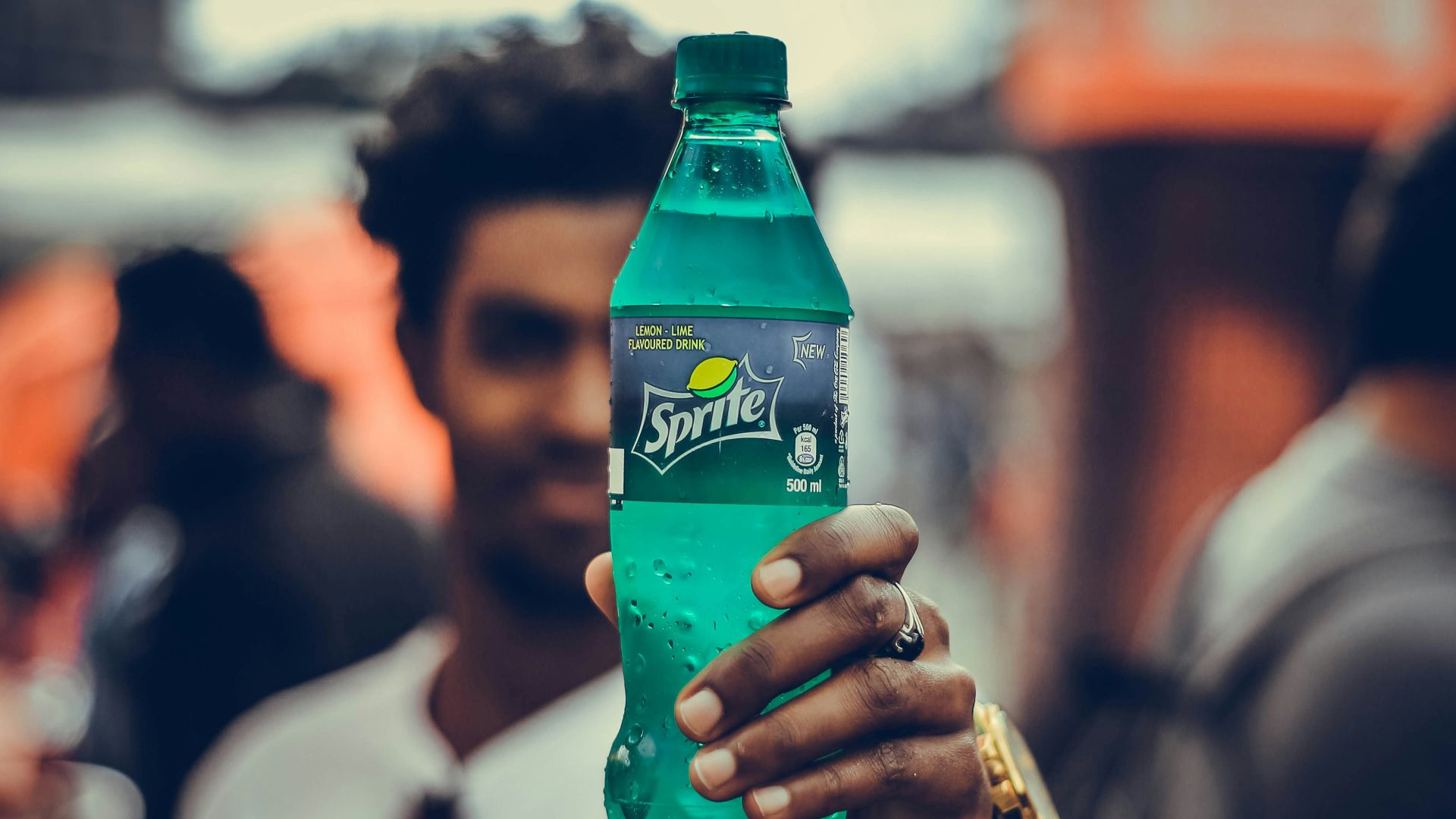 man wearing white shirt holding Sprite bottle