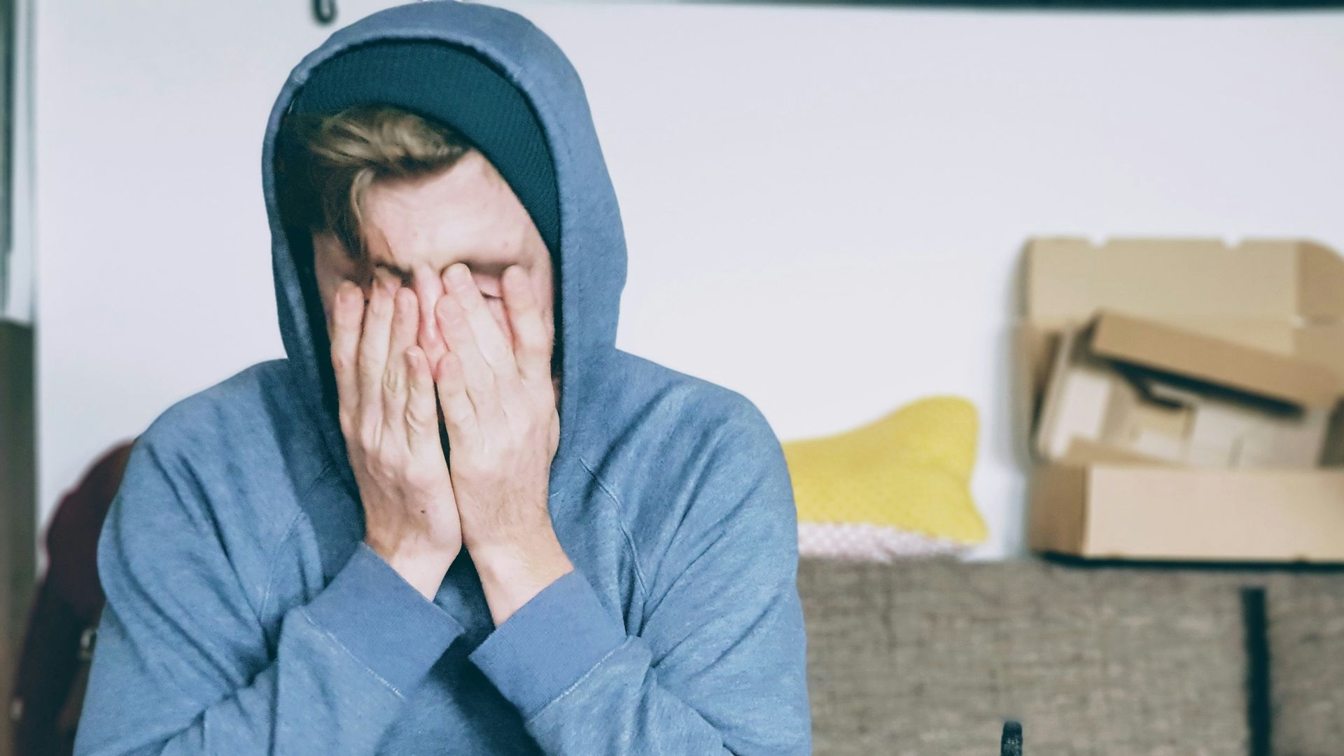 man covering face with both hands while sitting on bench