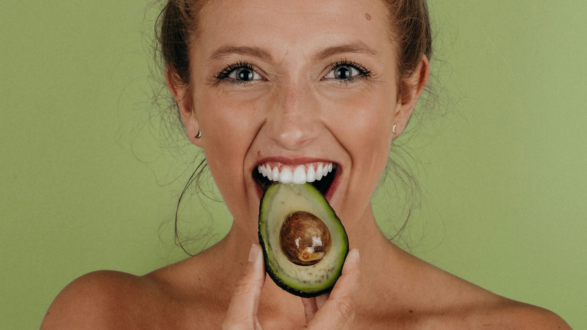 woman holding sliced avocado
