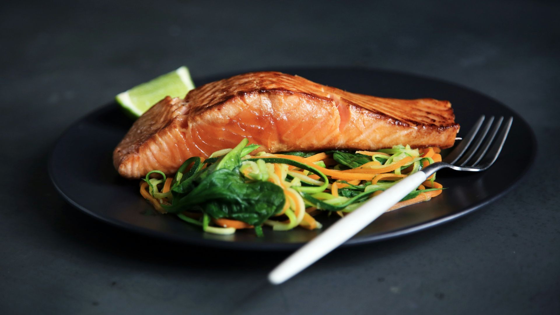 grilled fish, cooked vegetables, and fork on plate